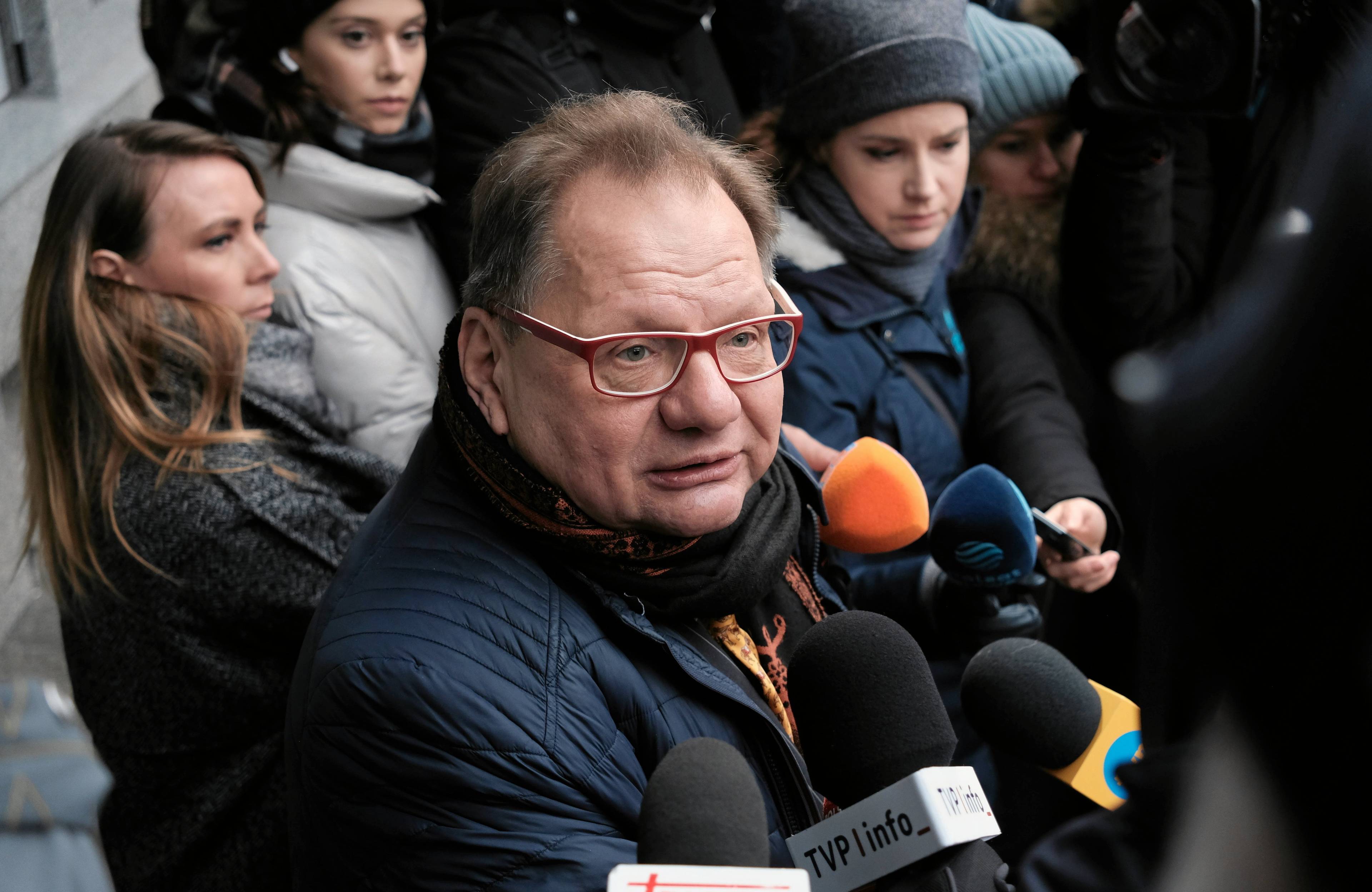 Mężczyzna w okularach w otoczeniu mikrofonów