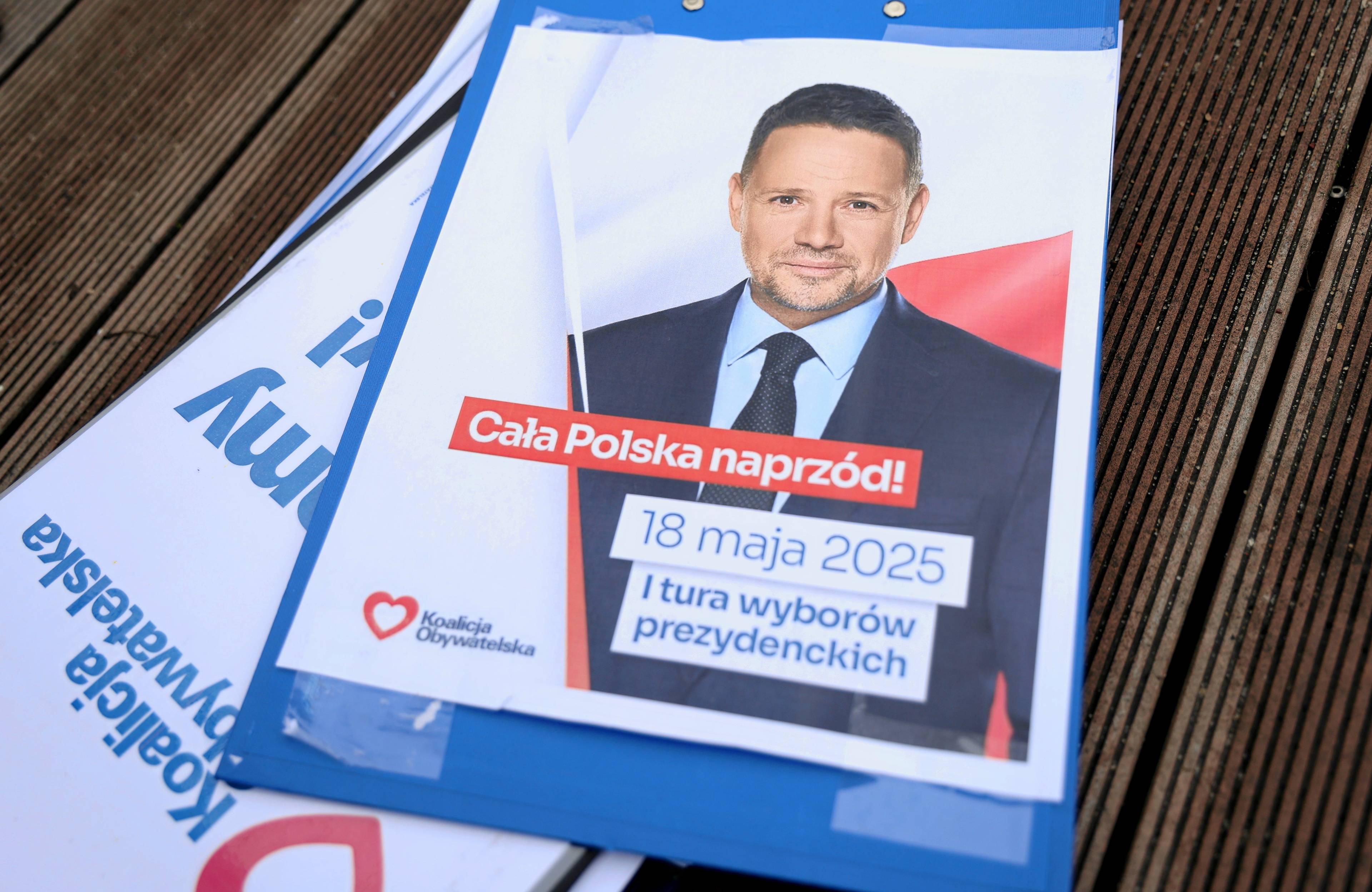 Na zdjęciu jest ulotka, na której widać uśmiechniętego mężczyznę ok. 50 lat. Jest w garniturze.