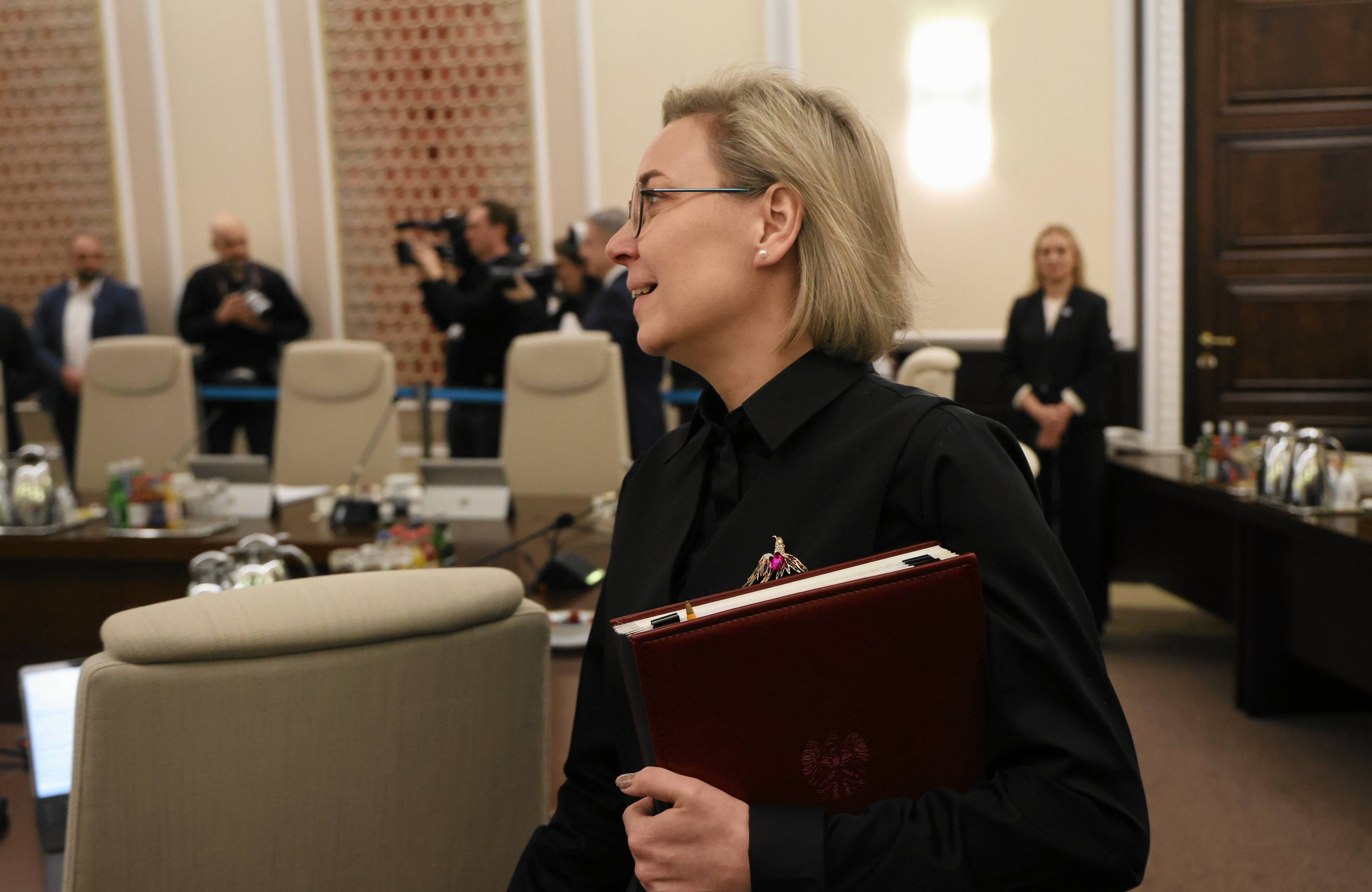 Jansowłosa kobieta z teczka na dokumenty pod pachą na sali posiedzeń rządu