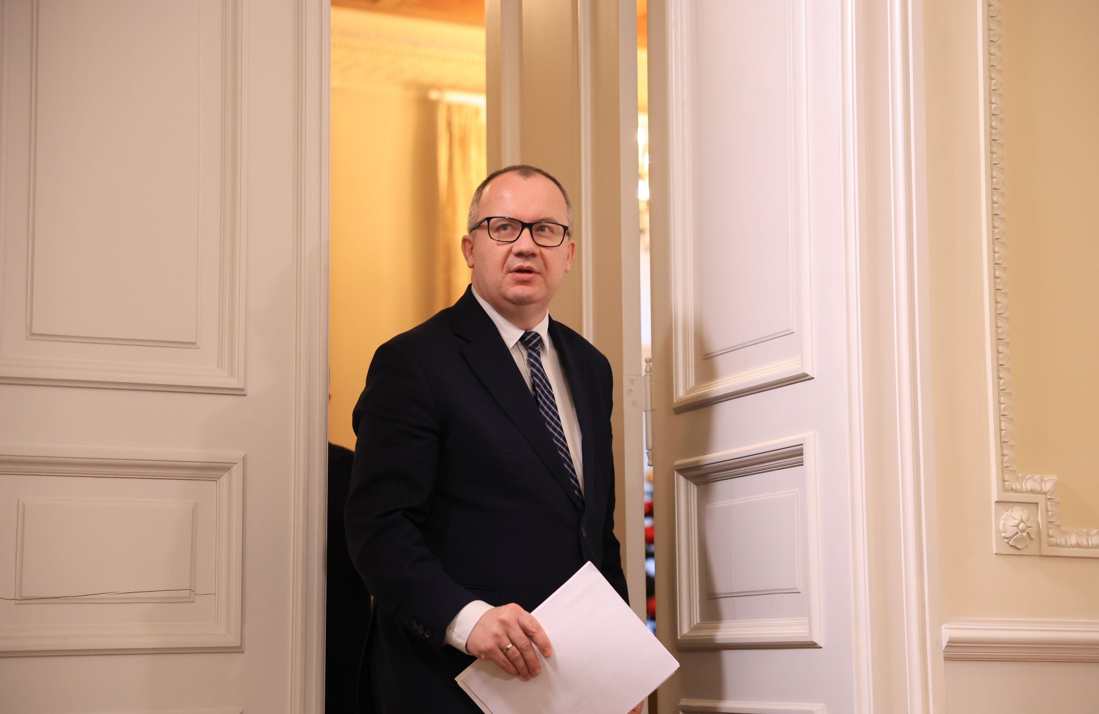 Adam Bodnar wychodzi przez duże drzwi, w ręce trzyma dokumenty