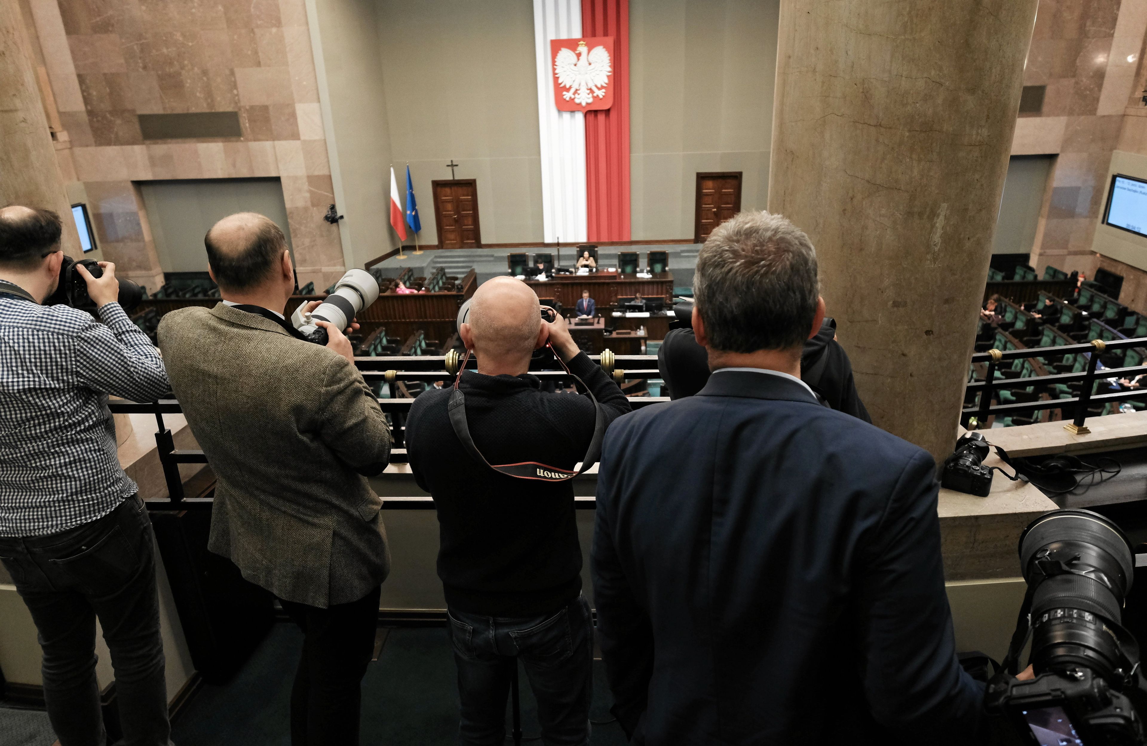 fotoreporterzy stoją na galerii w sejmie