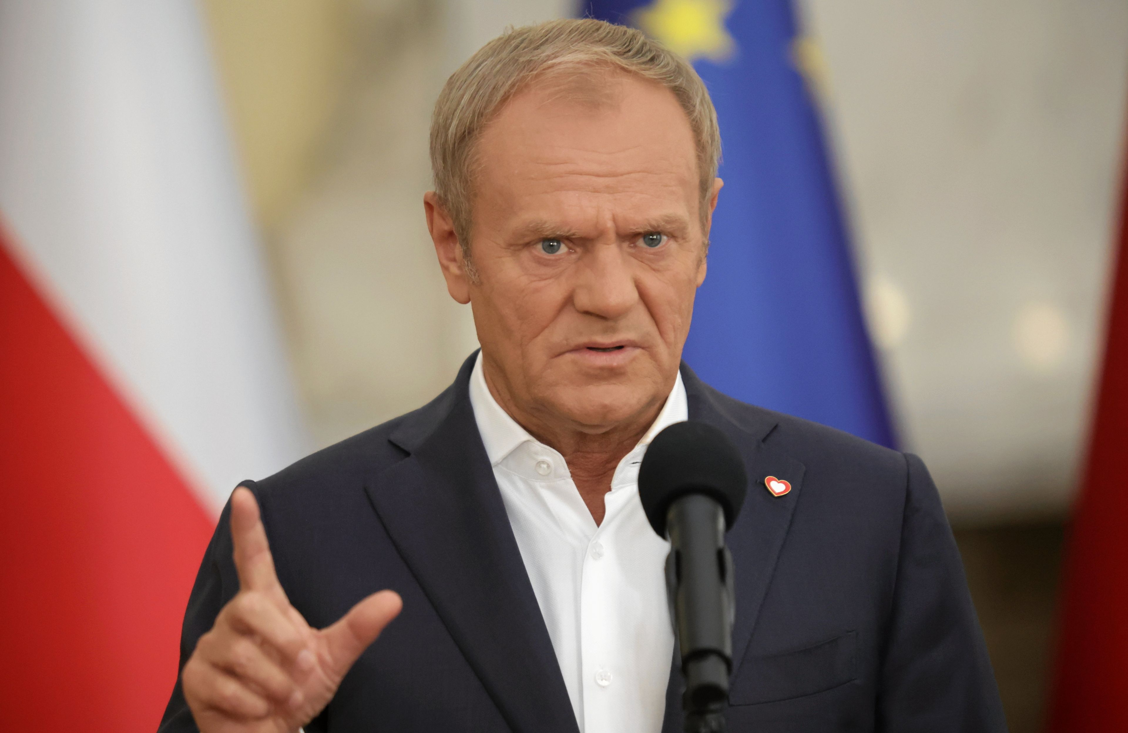 Donald Tusk na tle flagi Polski i flagi UE