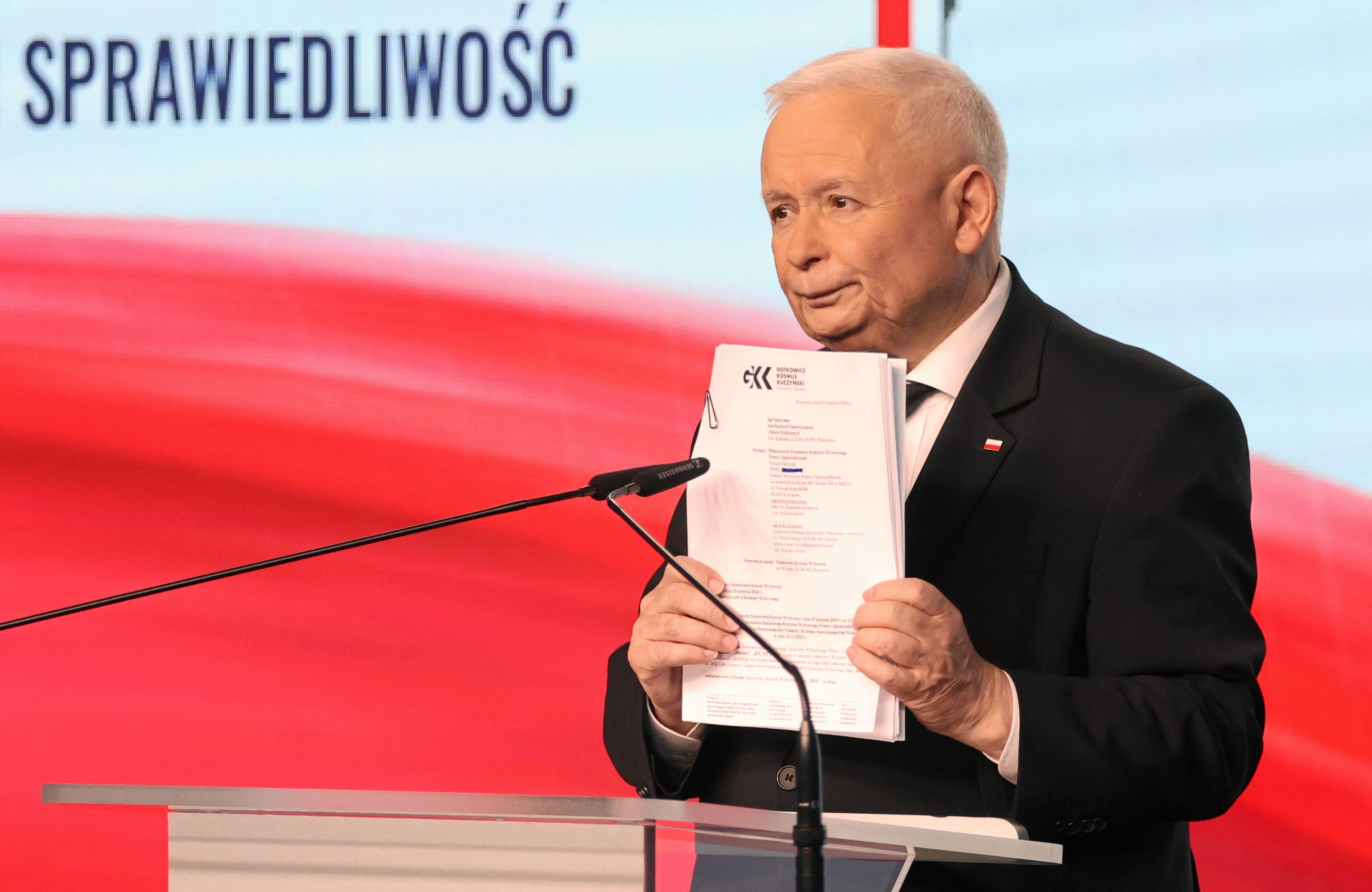 Jarosław Kaczyński na mównicy pokazuje plik dokumentów