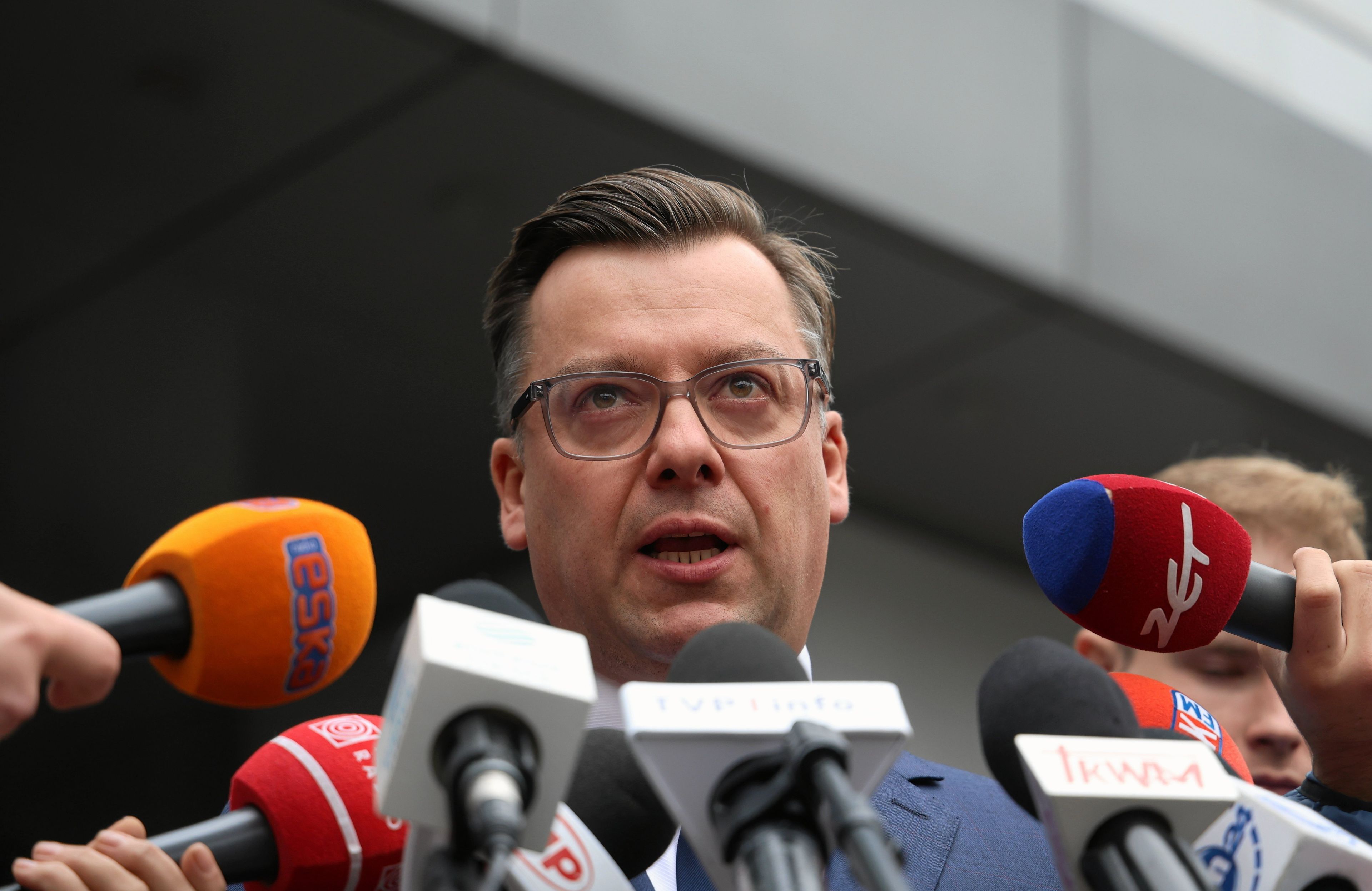 Prokurator Przemysław Nowak podczas konferencji prasowej przed licznymi mikrofonami mediów