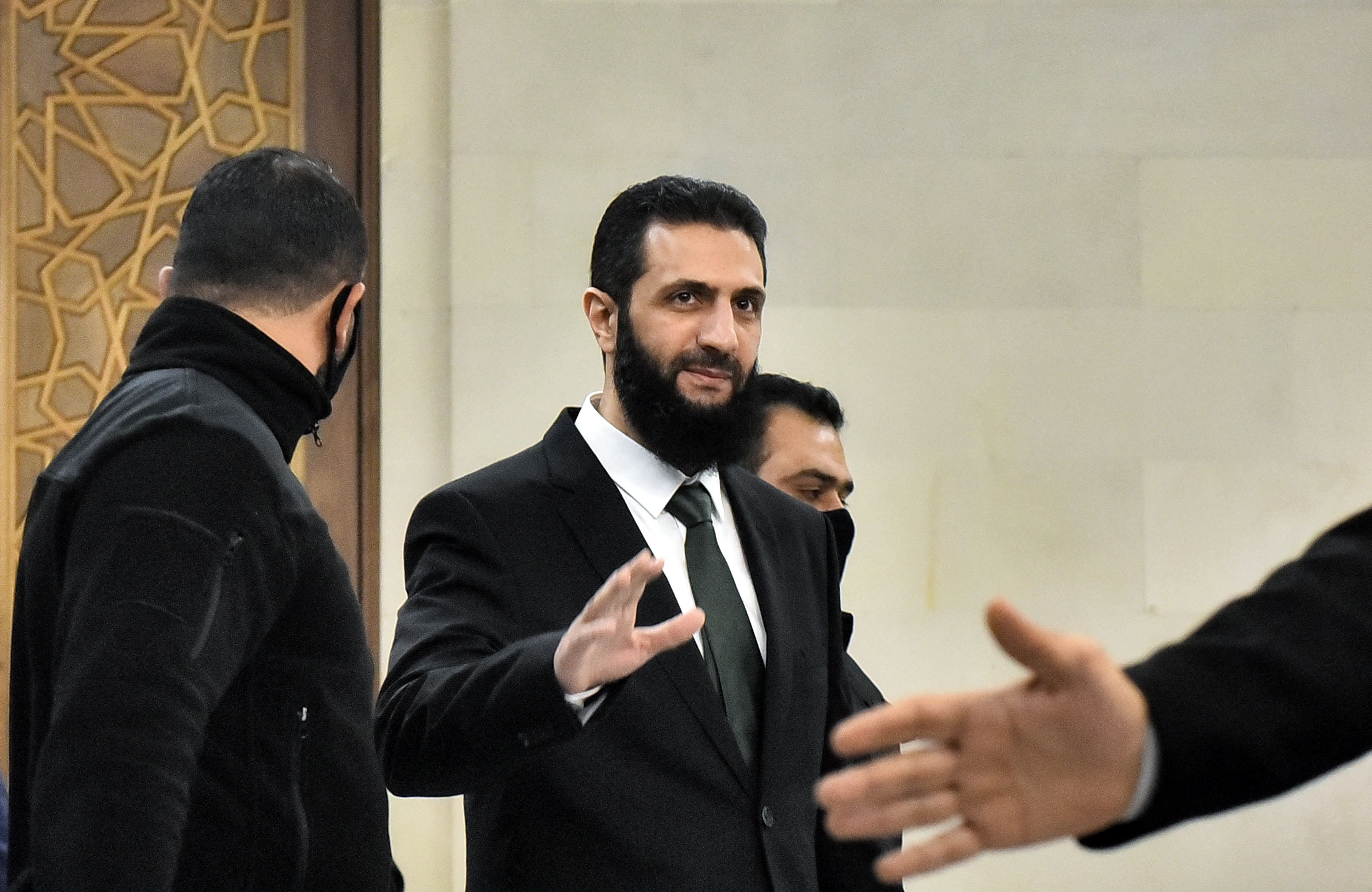 Syryjski lider Ahmed asz-Szar'a pozdrawia dłonią kogoś poza kadrem