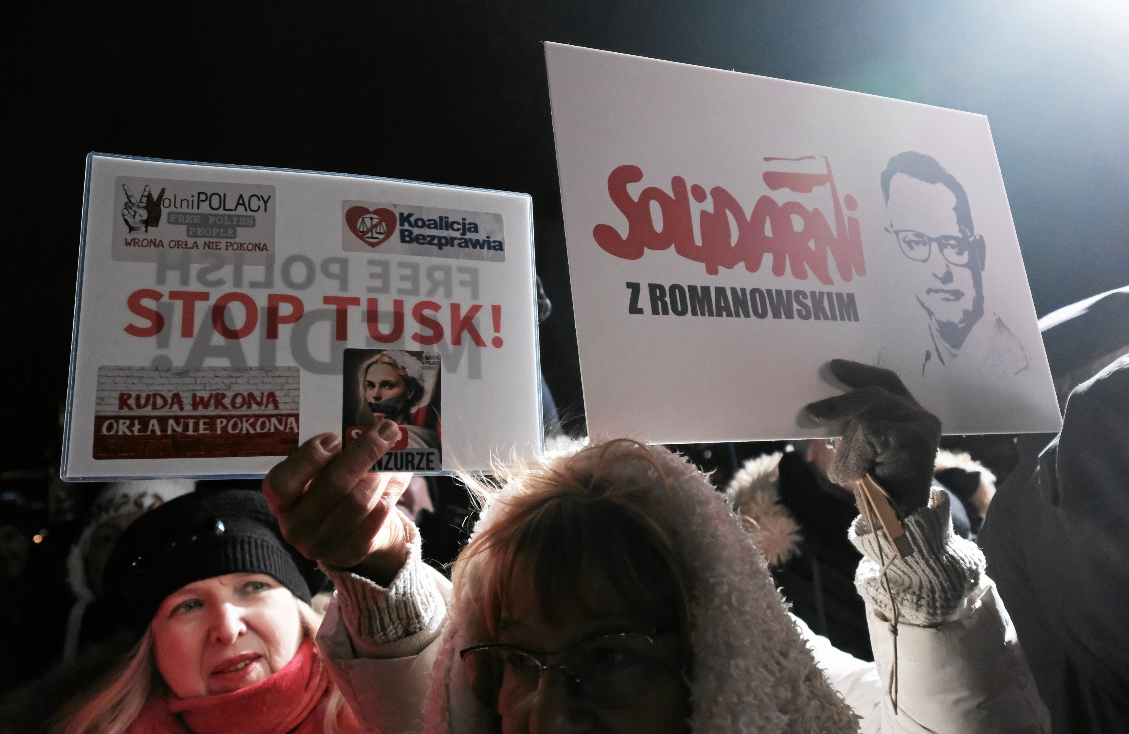 Grupka osob protestujacych podczas 43. rocznicy wprowazenia stanu wojennego. Trzymaja transperenty z napisem "Solidarni z Romanowskim" oraz "Stop Tusk"