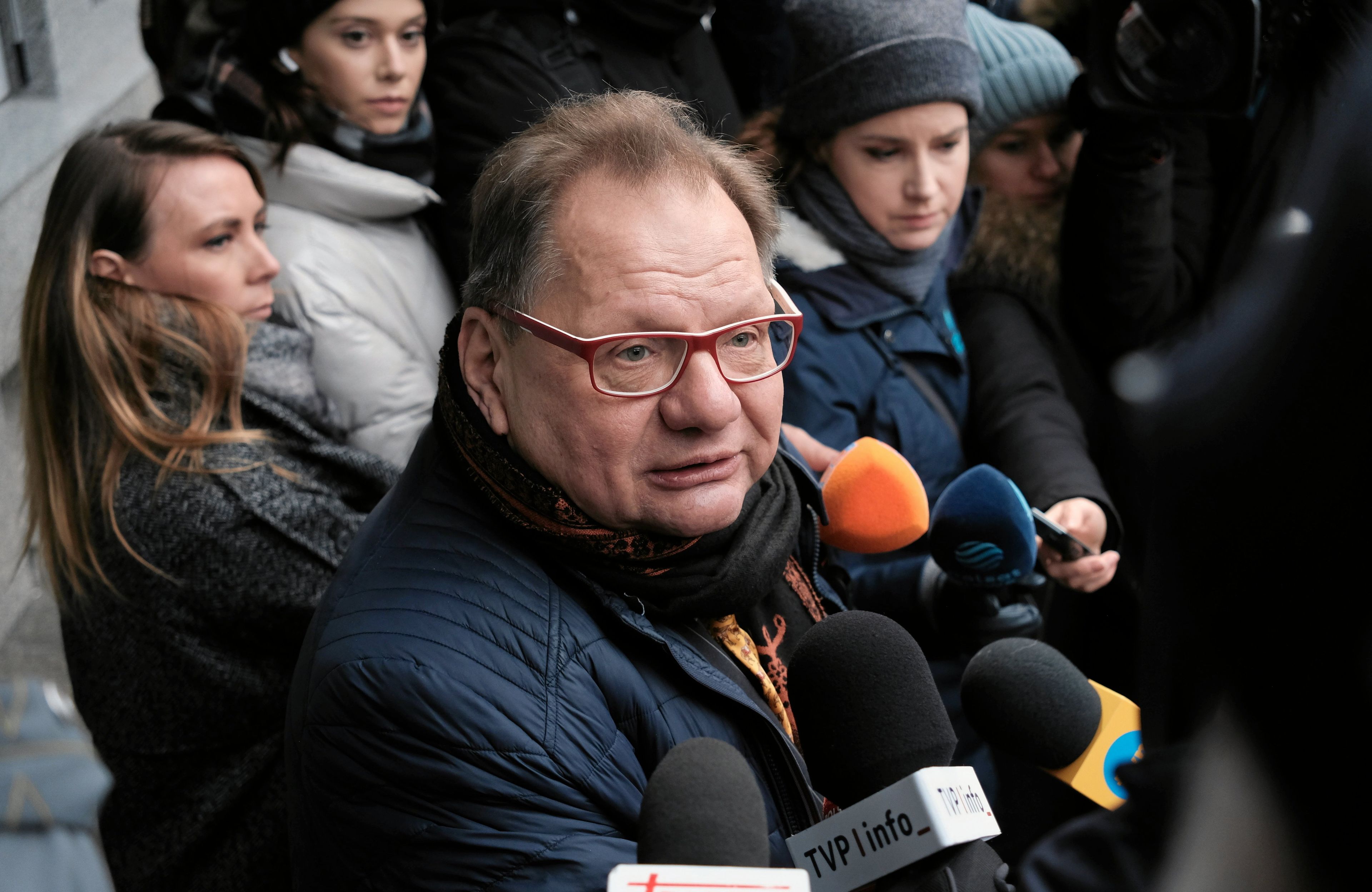 Mężczyzna w okularach w otoczeniu mikrofonów