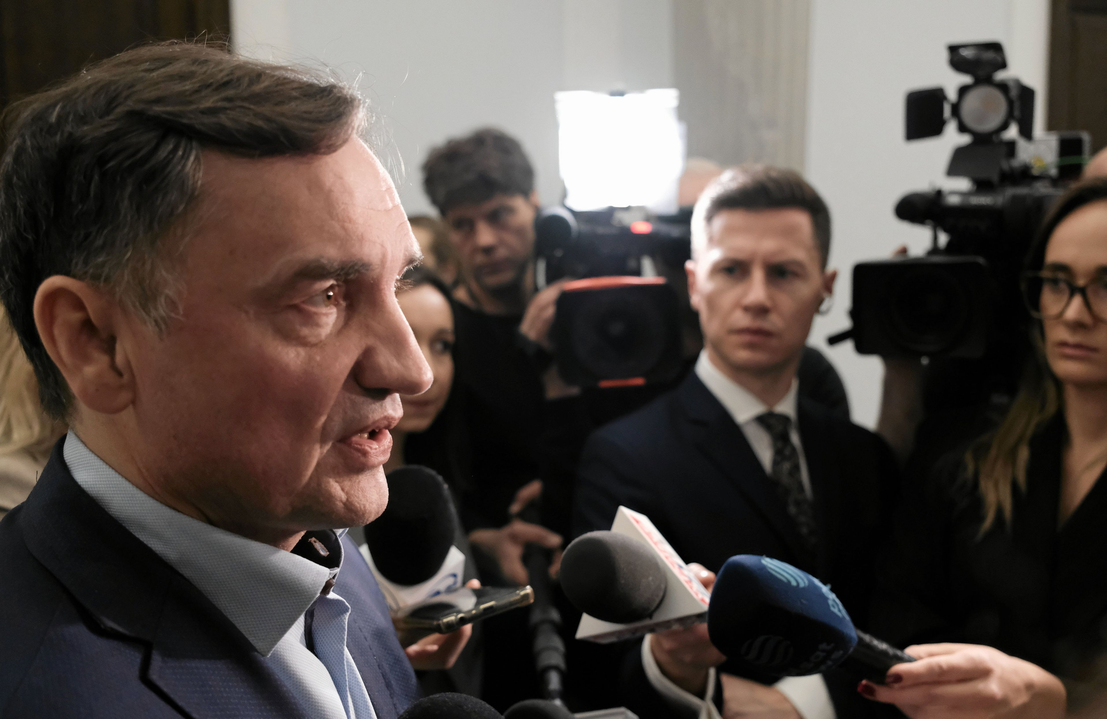 Mężczyzna widoczny z profilu, z mikrofonami podetkniętymi pod nos.