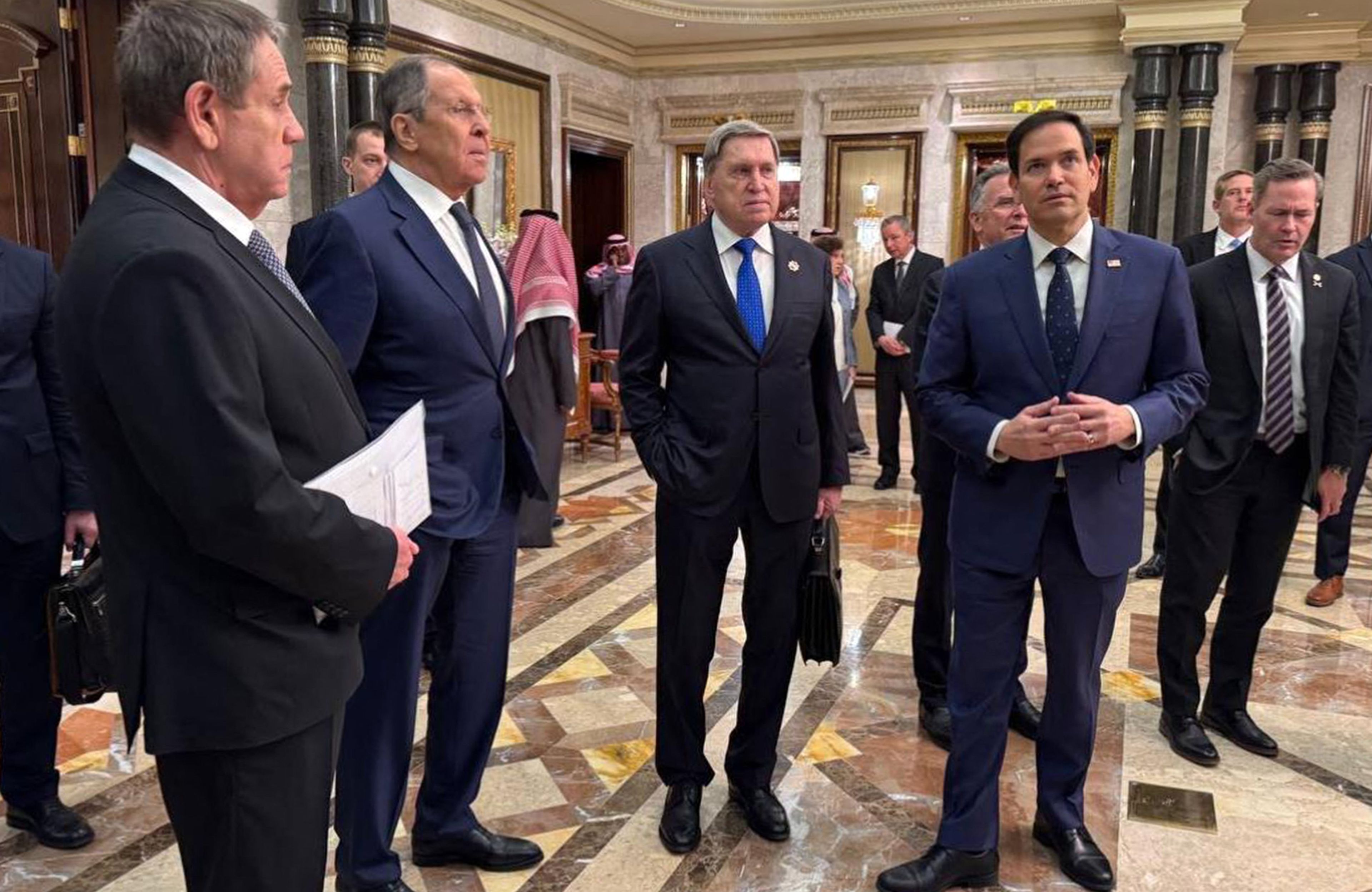 Czterech mężczyzn w garniturach stoi w eleganckim korytarzu