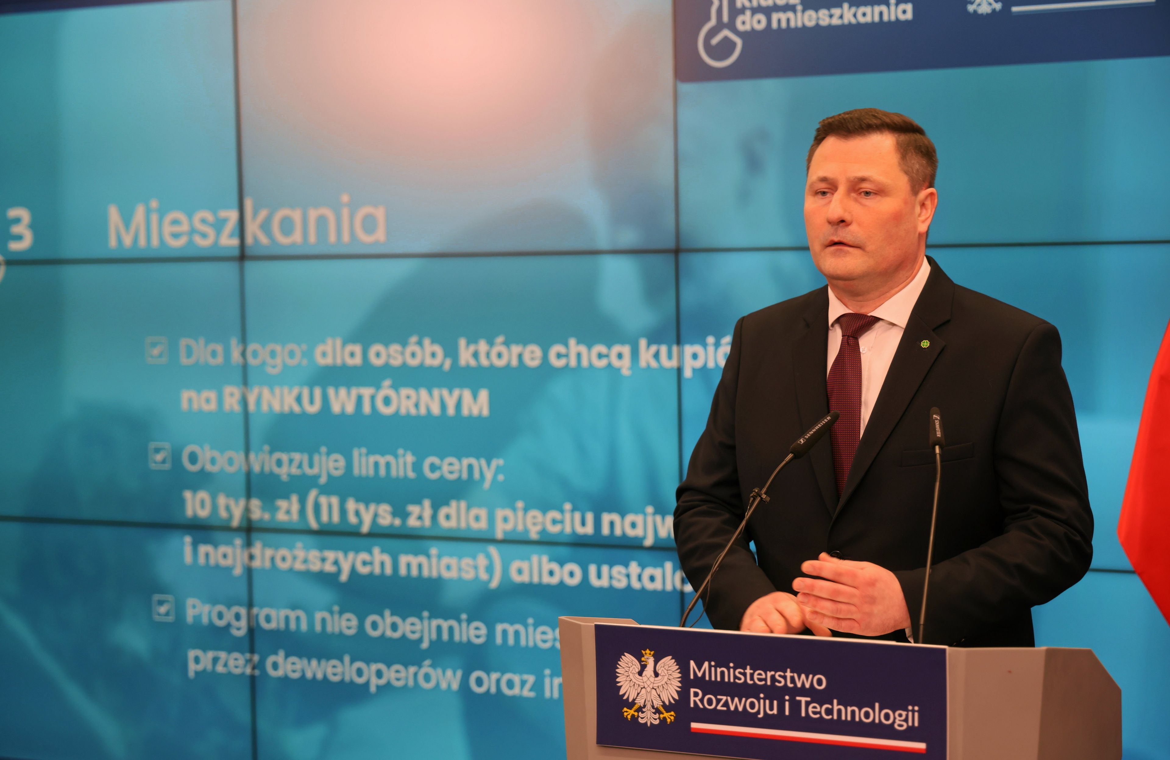 minister stoi na tle ekranu