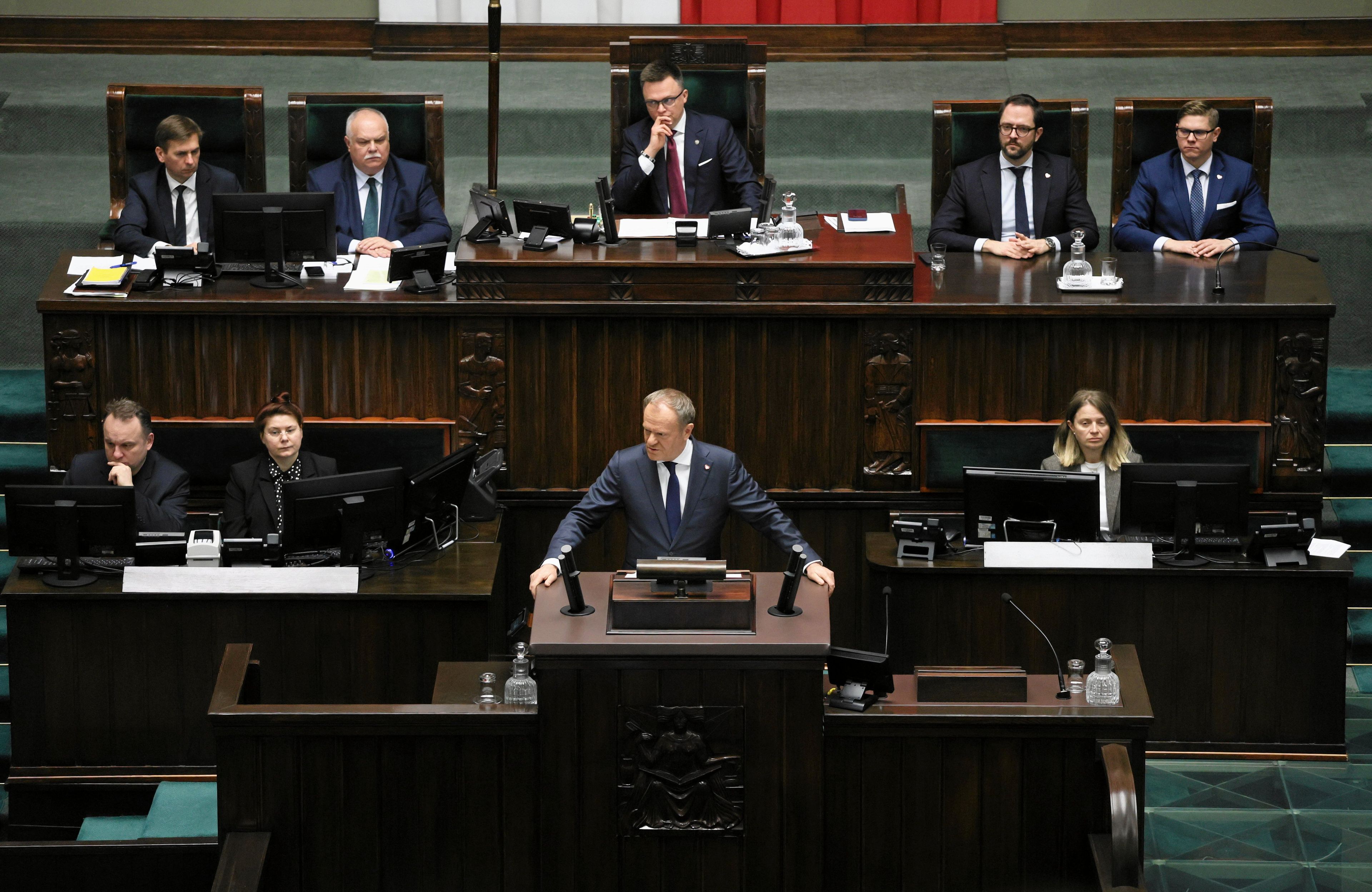 Premier Donald Tusk występuje w Sejmie, widok na mównicę i górującego nad nim marszałka Hołownię
