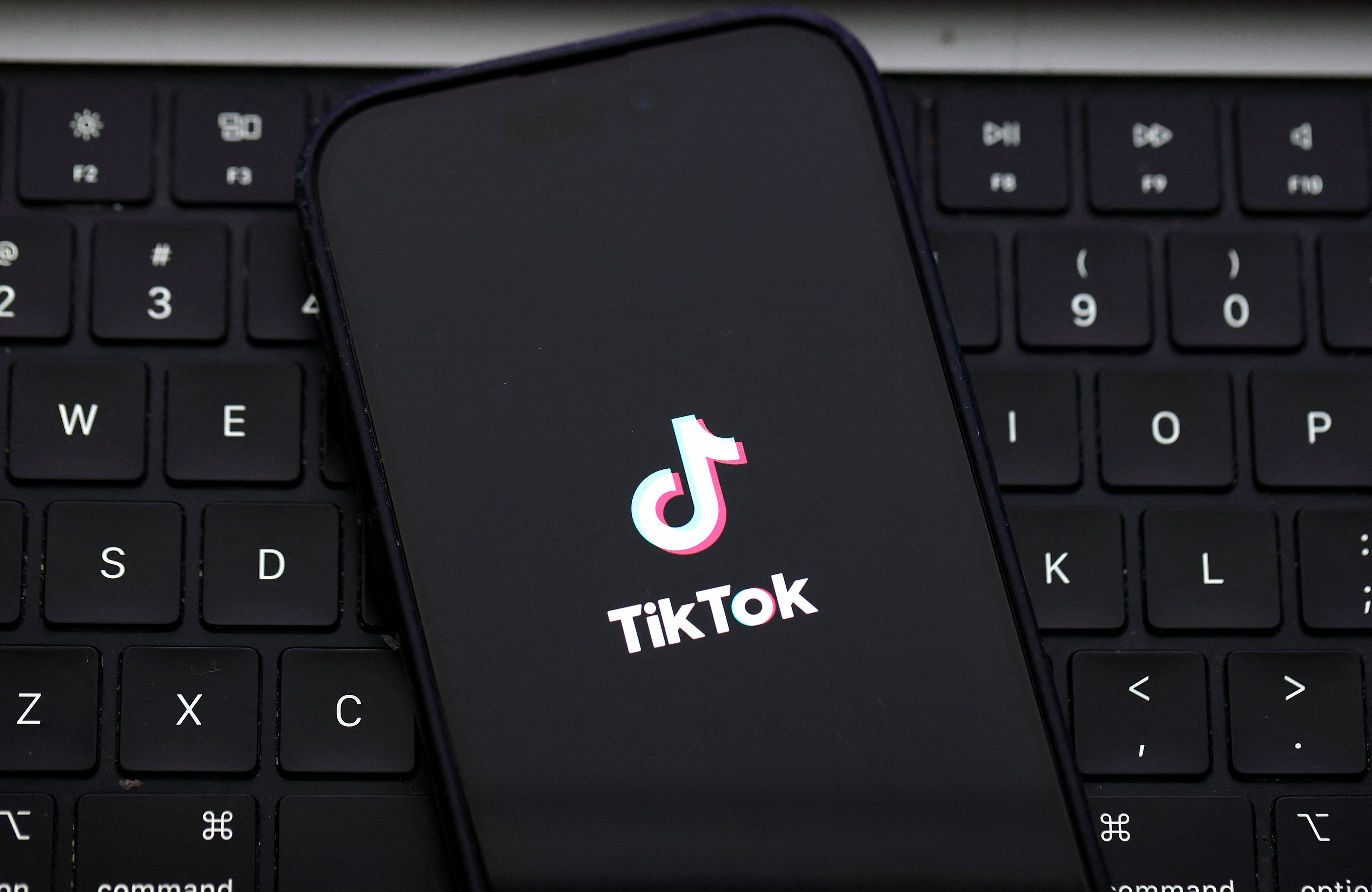 Telefon z logotypem TikToka leżący na klawiaturze