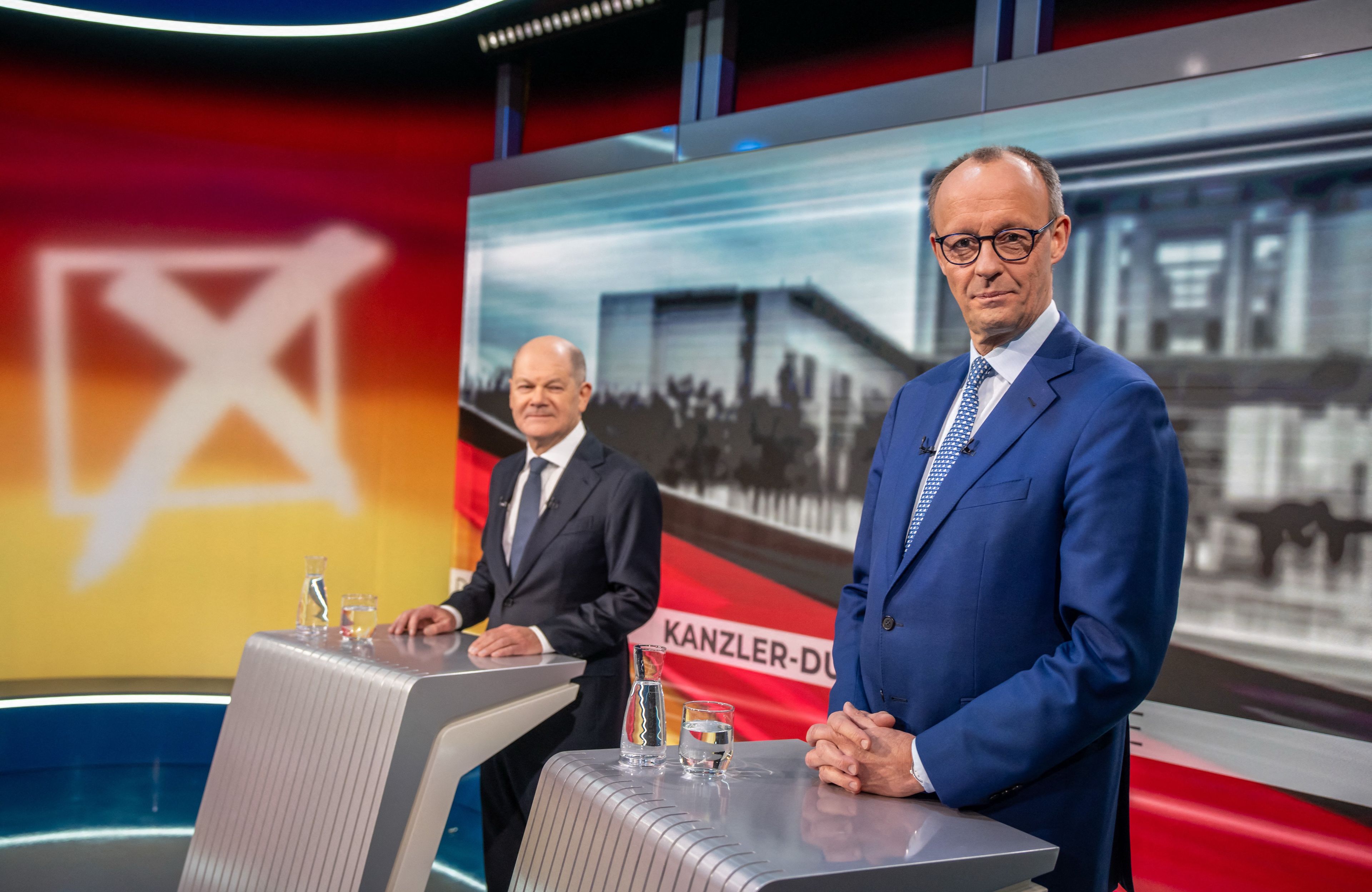 Dwaj mężczyźni w garniturach przy pulpitach telewizyjnych podczas debaty