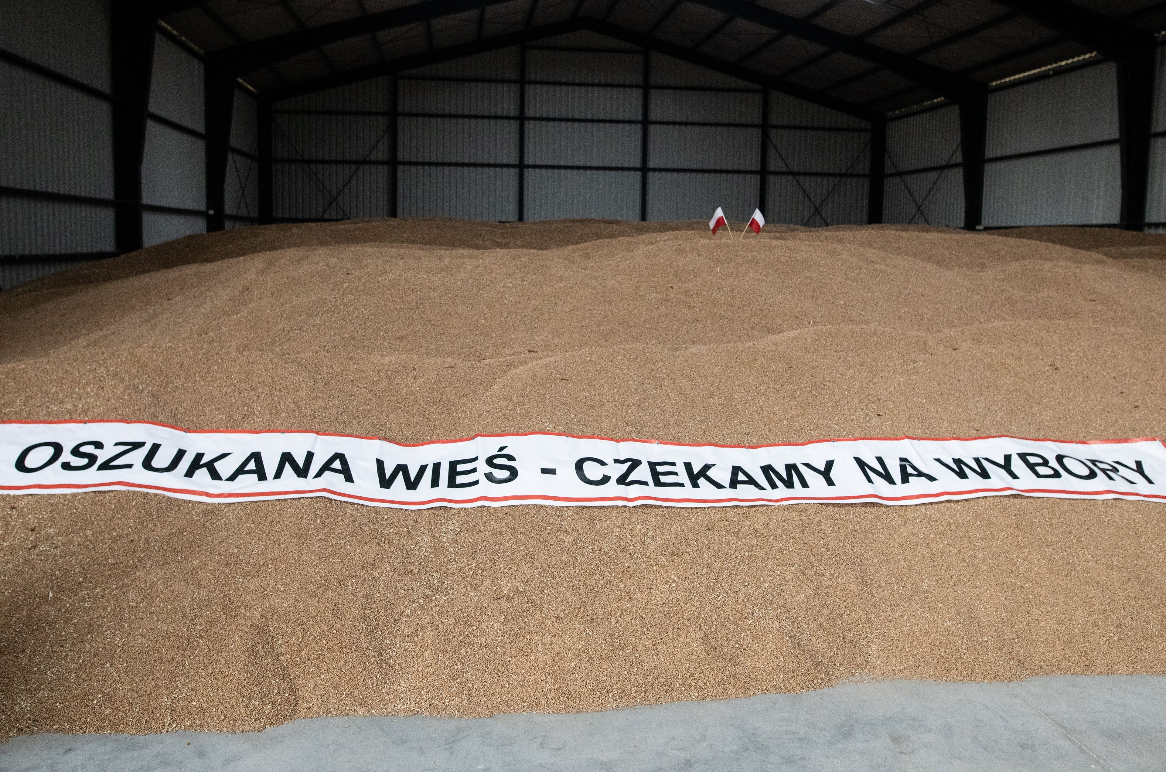 Ziarna pszenicy, na nich transparent z napisem "Oszukana wieś"