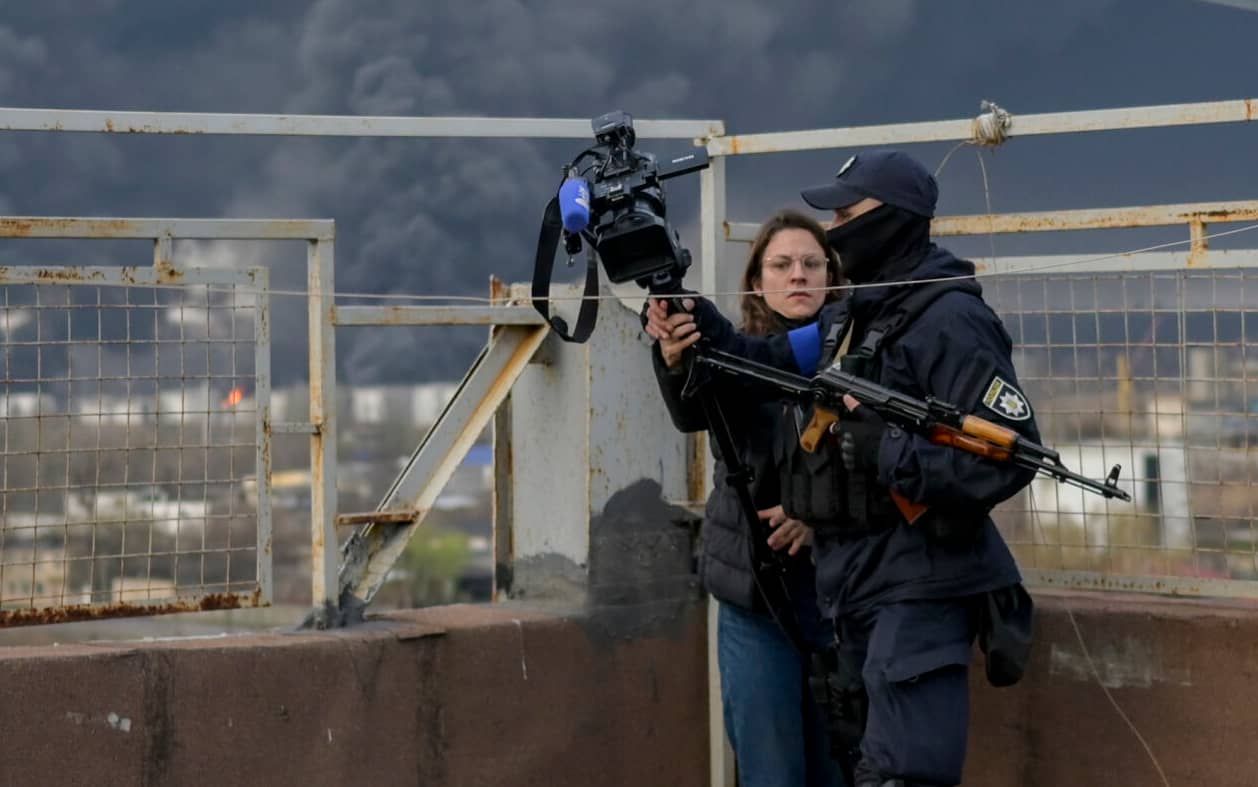 A Ukranian security officer keeps the press away as smoke rises after an attack by Russian army in Odessa, on April 3, 2022. - Air strikes rocked Ukraine's strategic Black Sea port Odessa early Sunday morning, according to an interior ministry official, after Kyiv had warned that Russia was trying to consolidate its troops in the south. (Photo by BULENT KILIC / AFP)