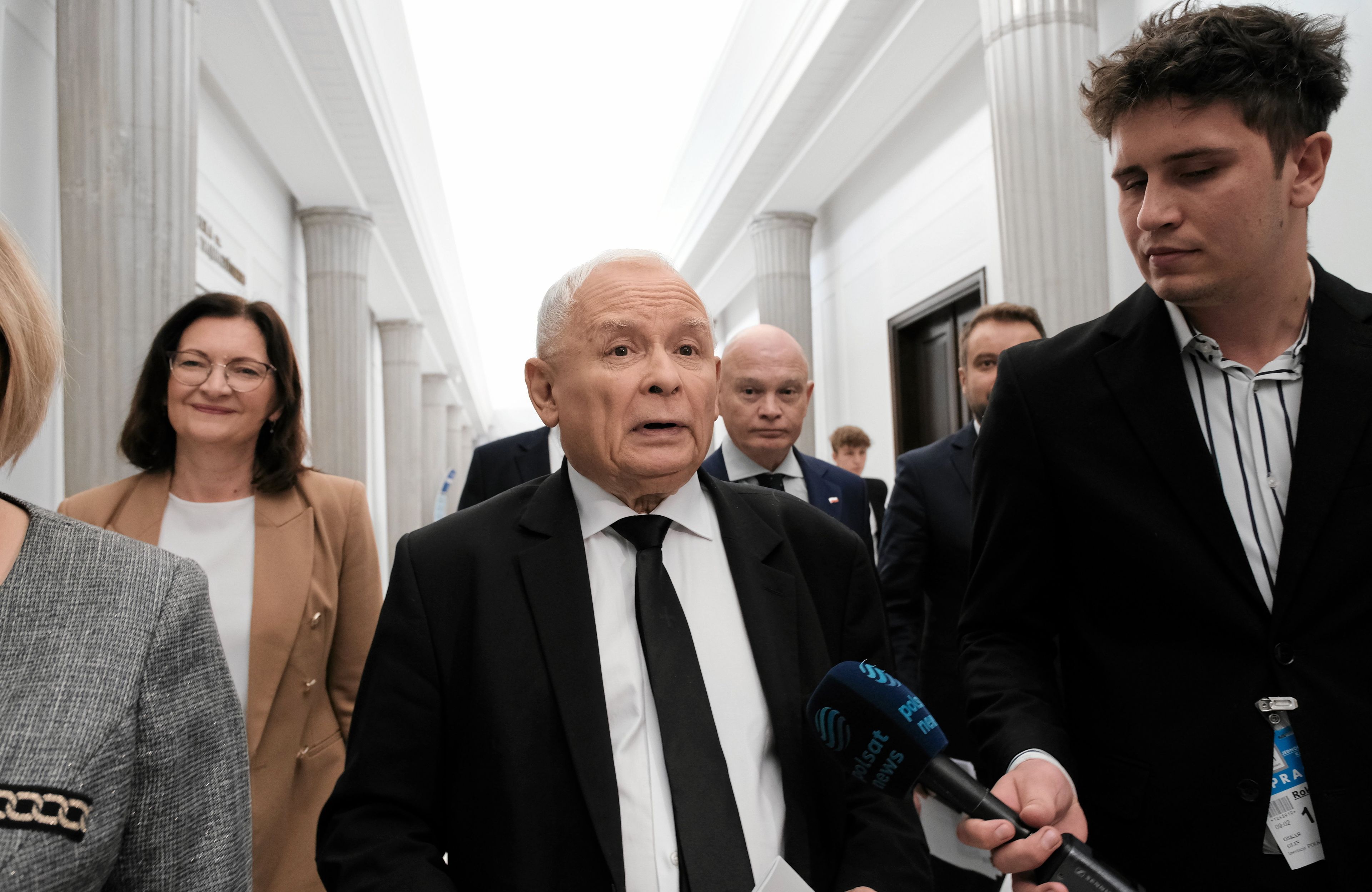 Starszy mężczyzna z otwartymi ustami w otoczeniu dziennikarzy
