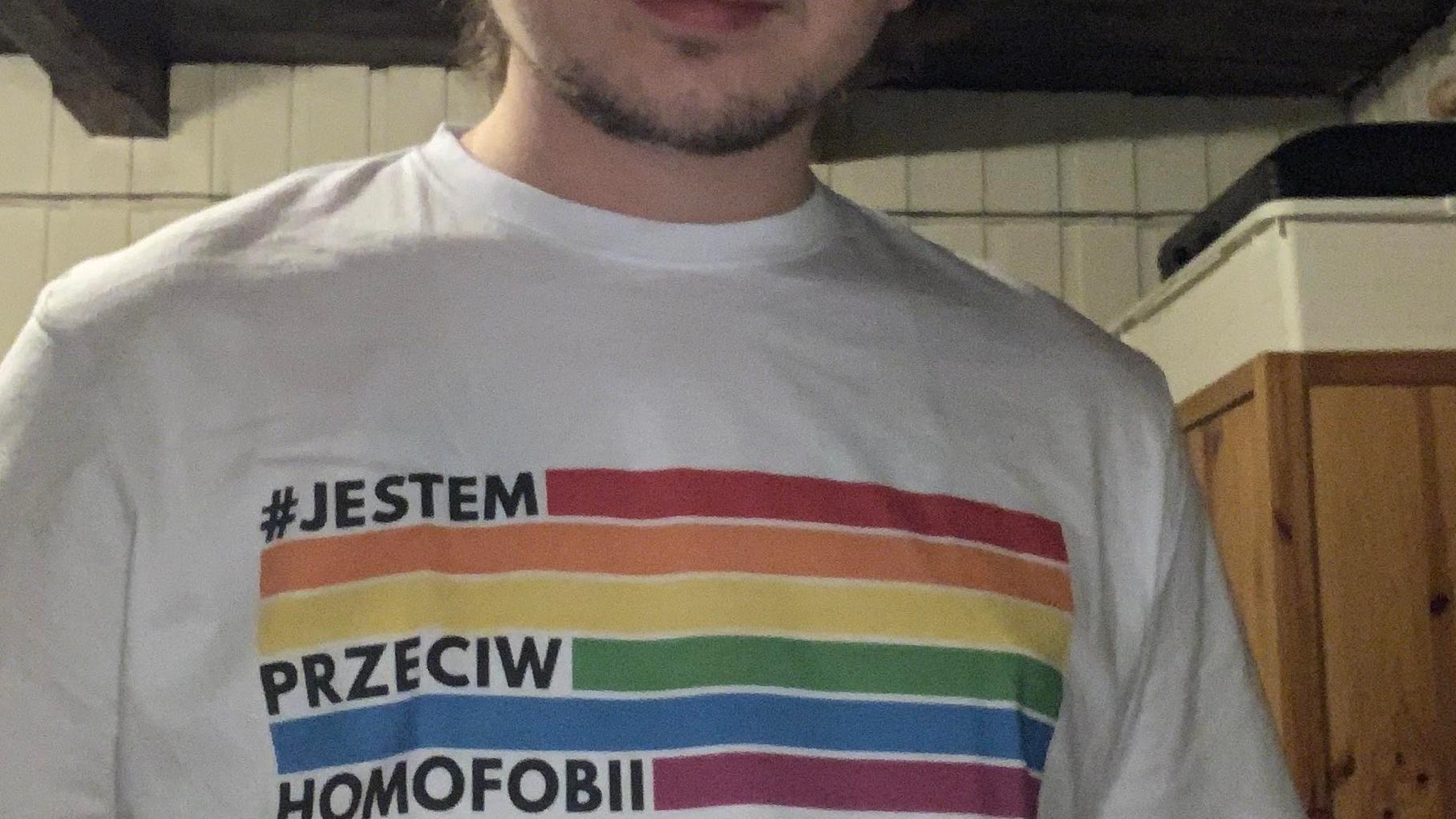 Młody męzczyzna w koszulce z motywem tęczy i napisem "Jestem przeciw homofobii"