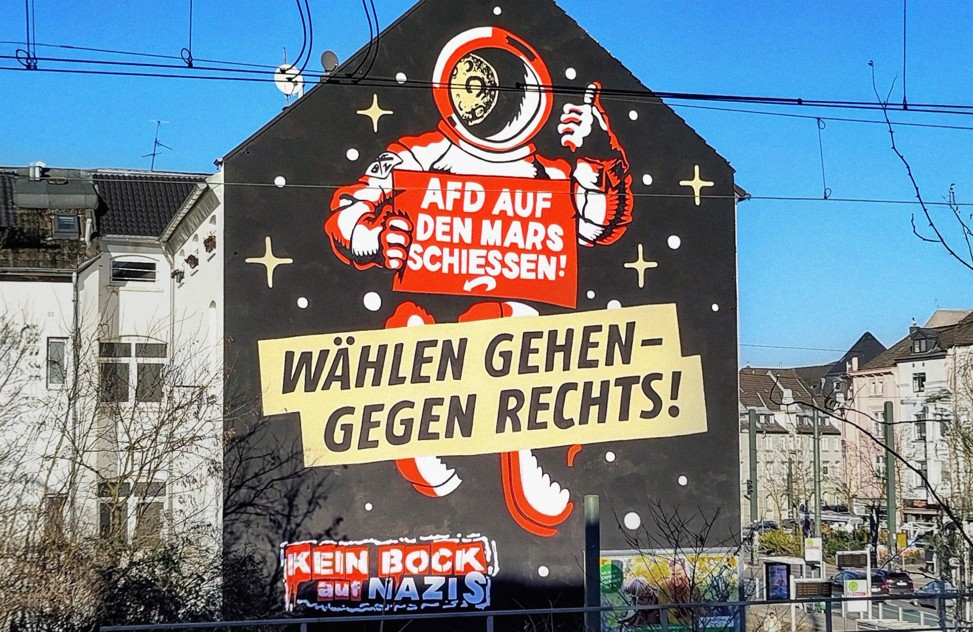 Mural z rysunkiem kosmonauty i hasłami w języku niemieckim