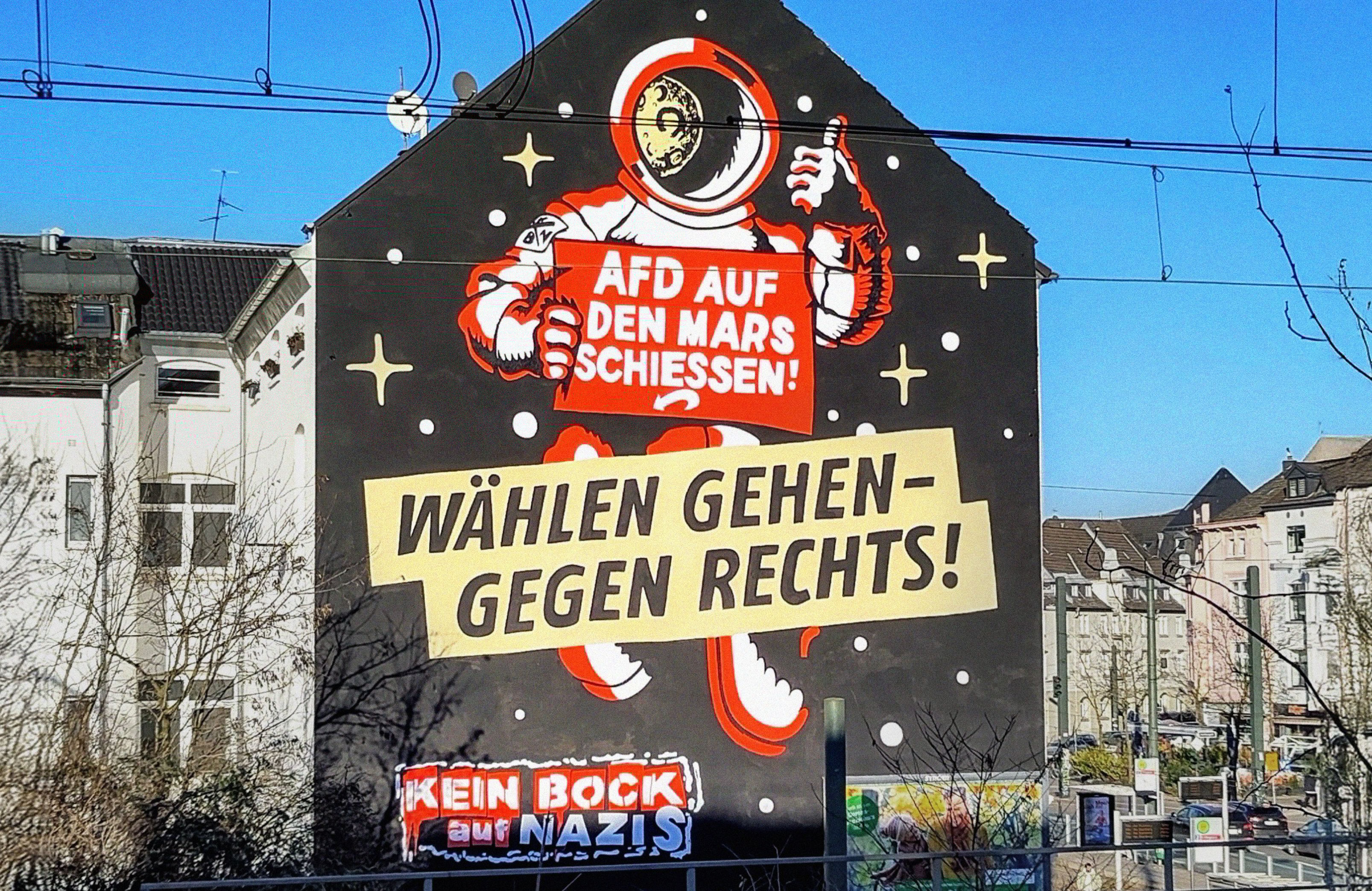 Mural z rysunkiem kosmonauty i hasłami w języku niemieckim