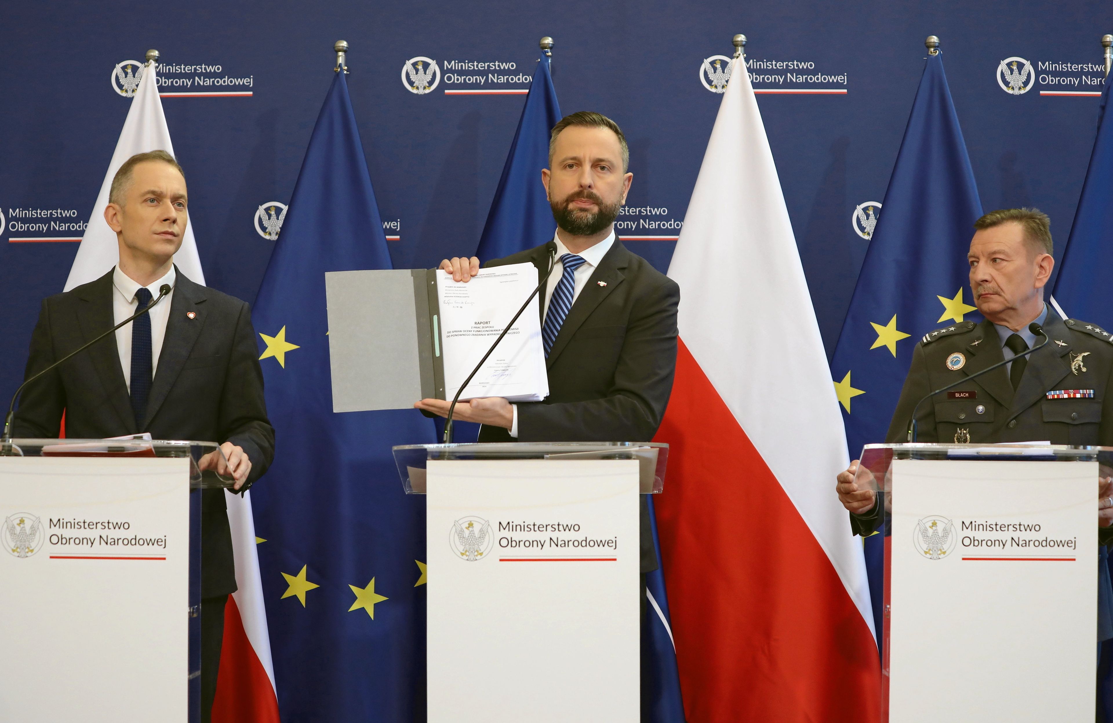Kosiniak-Kamysz trzyma raport ds. komisji smoleńskiej, obok niego Cezary Tomczyk w garniturze i plk pil. Leszek Blach w mundurze