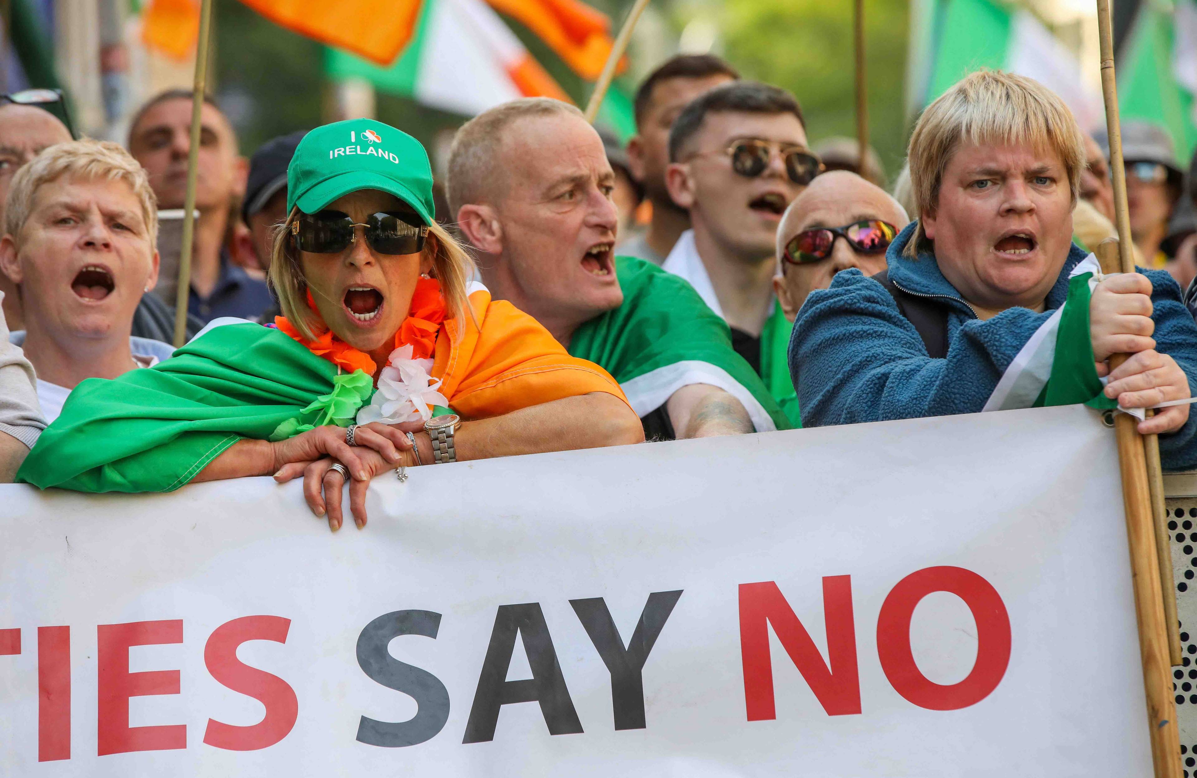 Protest przeciwko imigrantom w Irlandii, uczestnicy protestu trzymaja baner z napisem w j. angielskim „nie" i wykrzykują hasła.