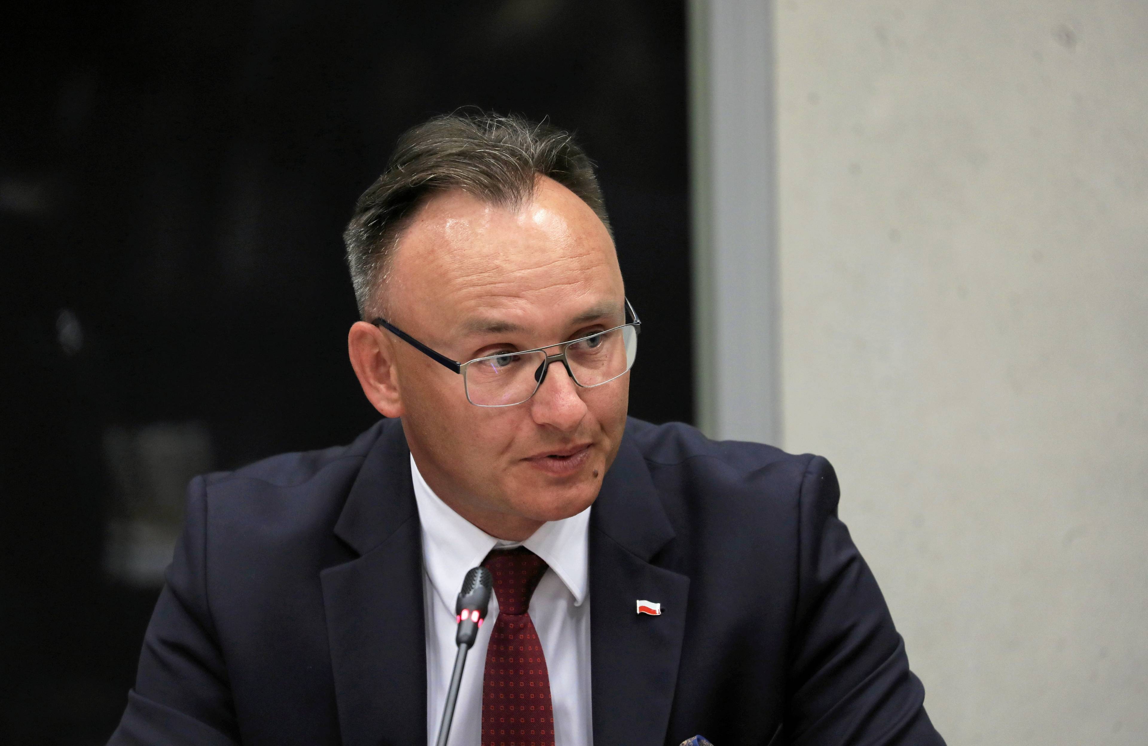 Mężczyzna w okulrach, lusawy, siedzi i mówi do mikrofonu