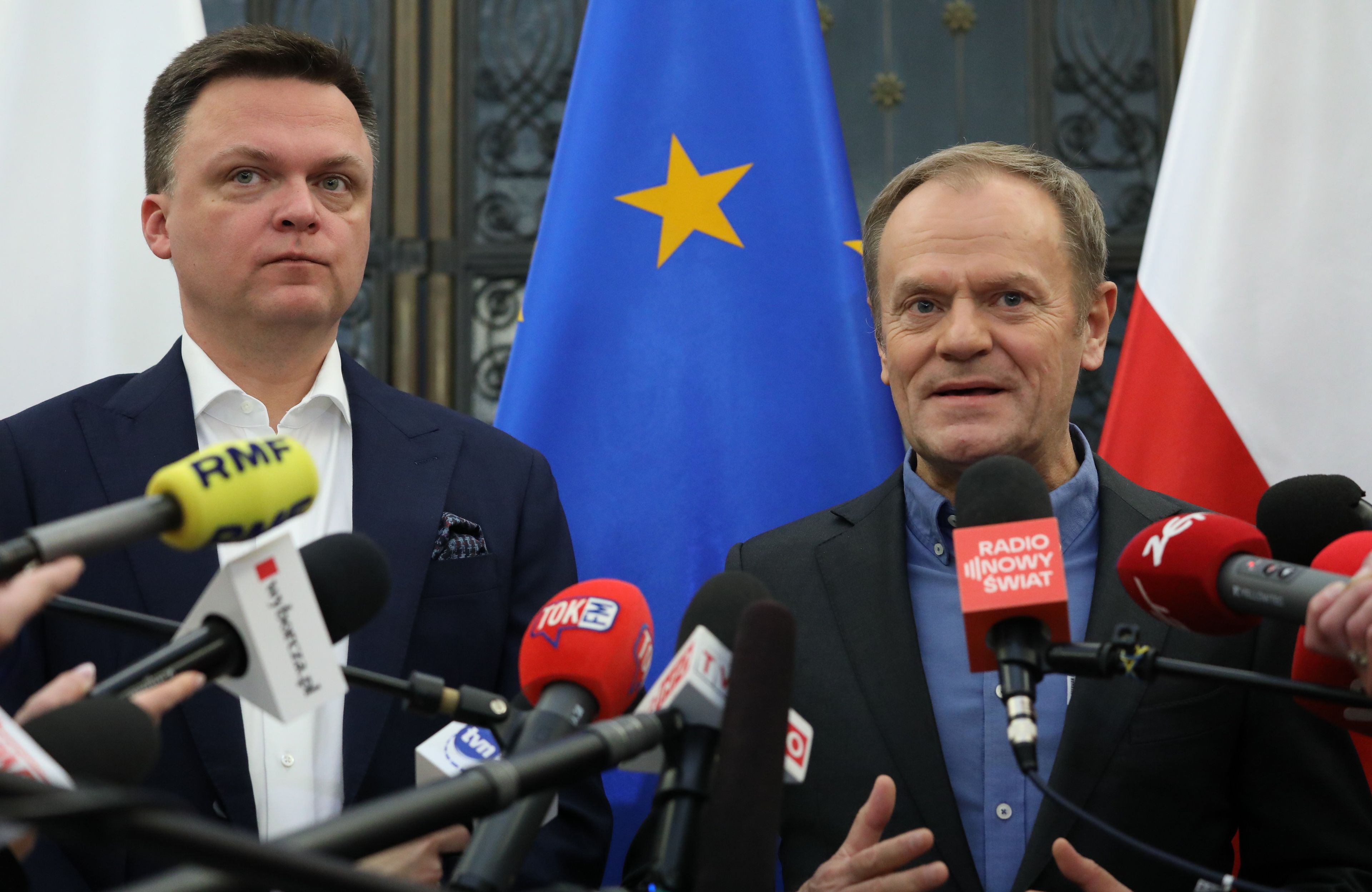 Tusk i Hołownia na tle polskich i europejskich flag