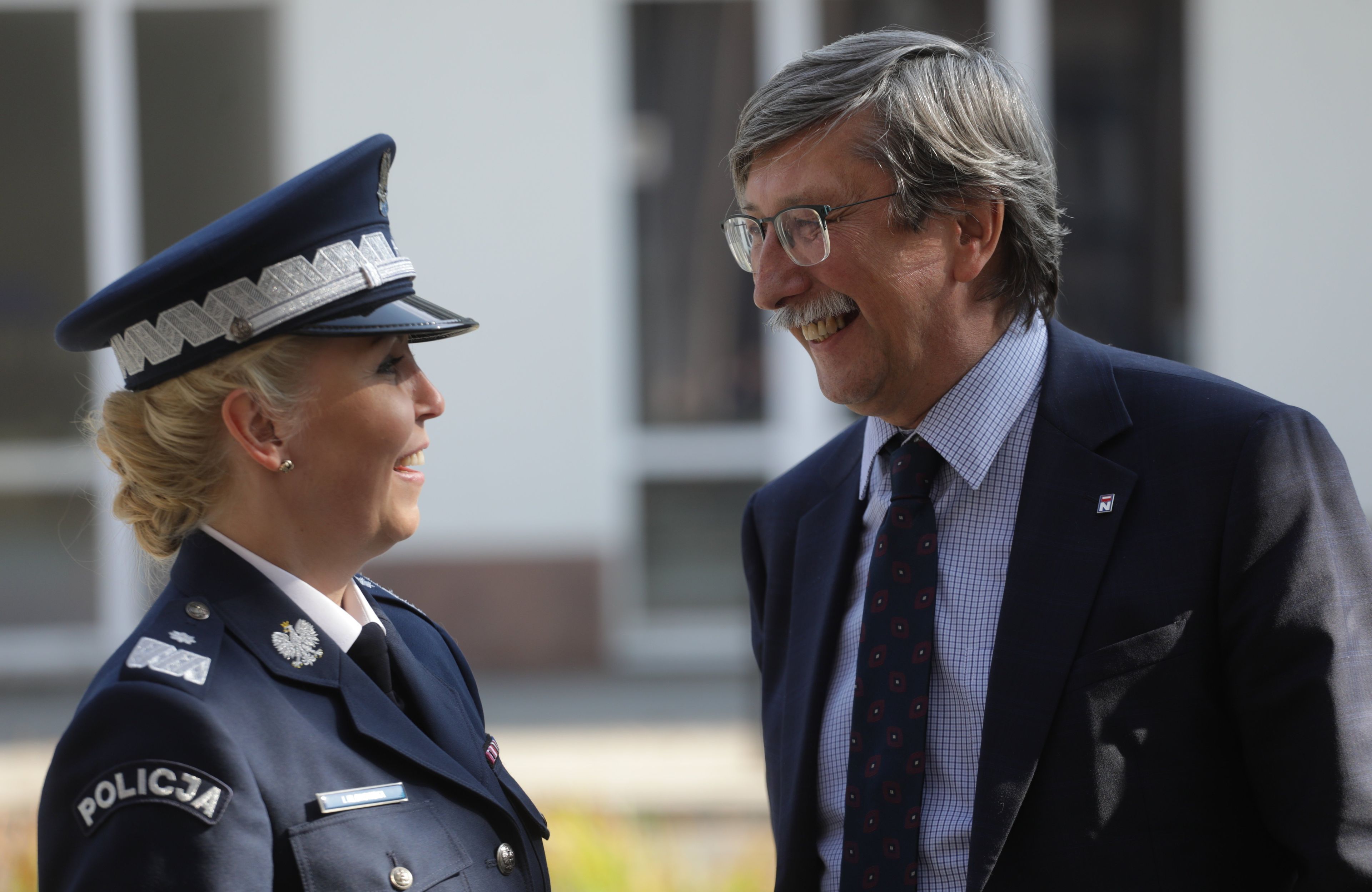 Kobieta w mundurze i mężczyzna w garniturze, z wąsami, śmieją się