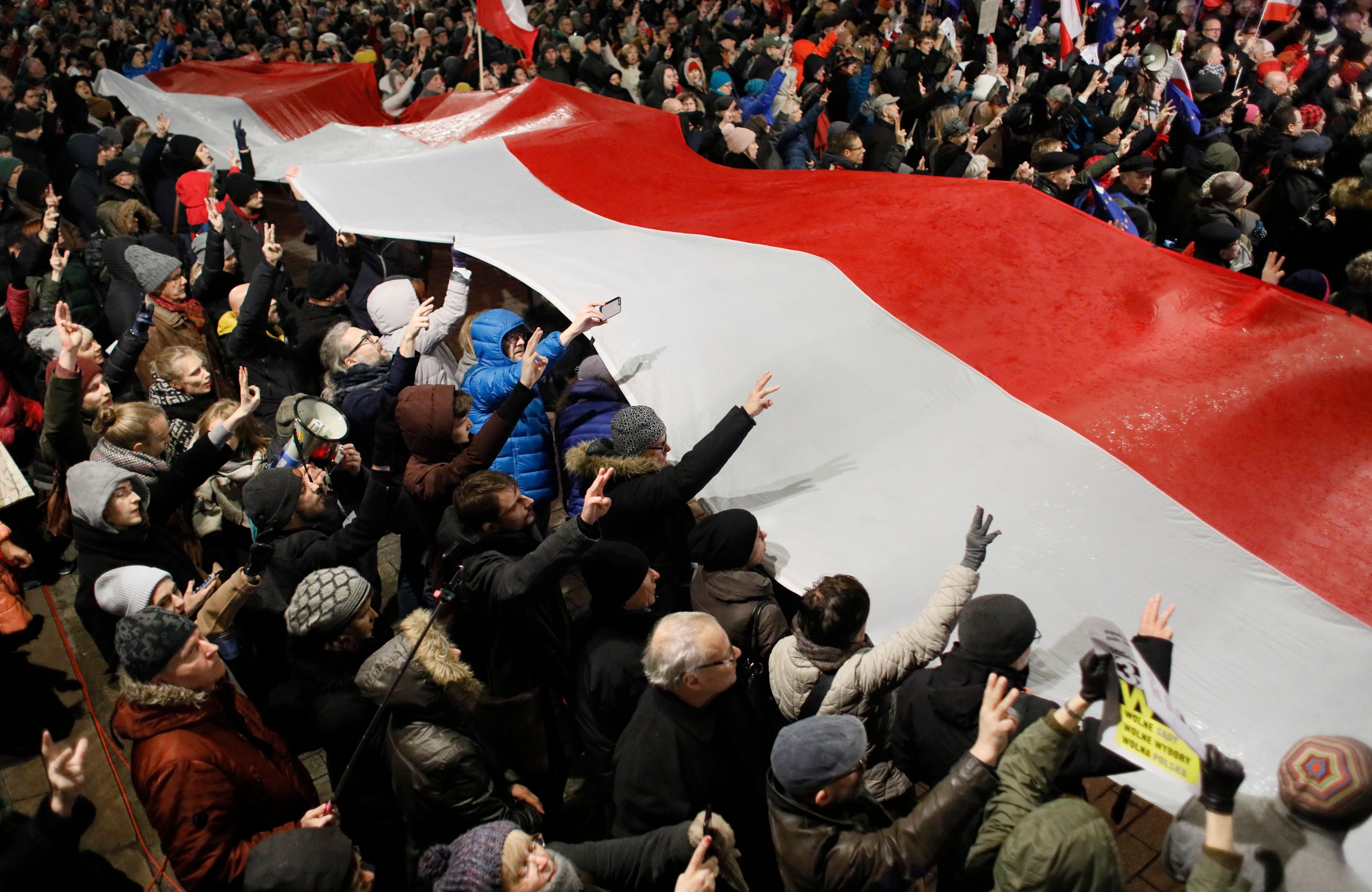 Demonstracja na ulicy. Protestujący trzymaja wielką flagę Polski