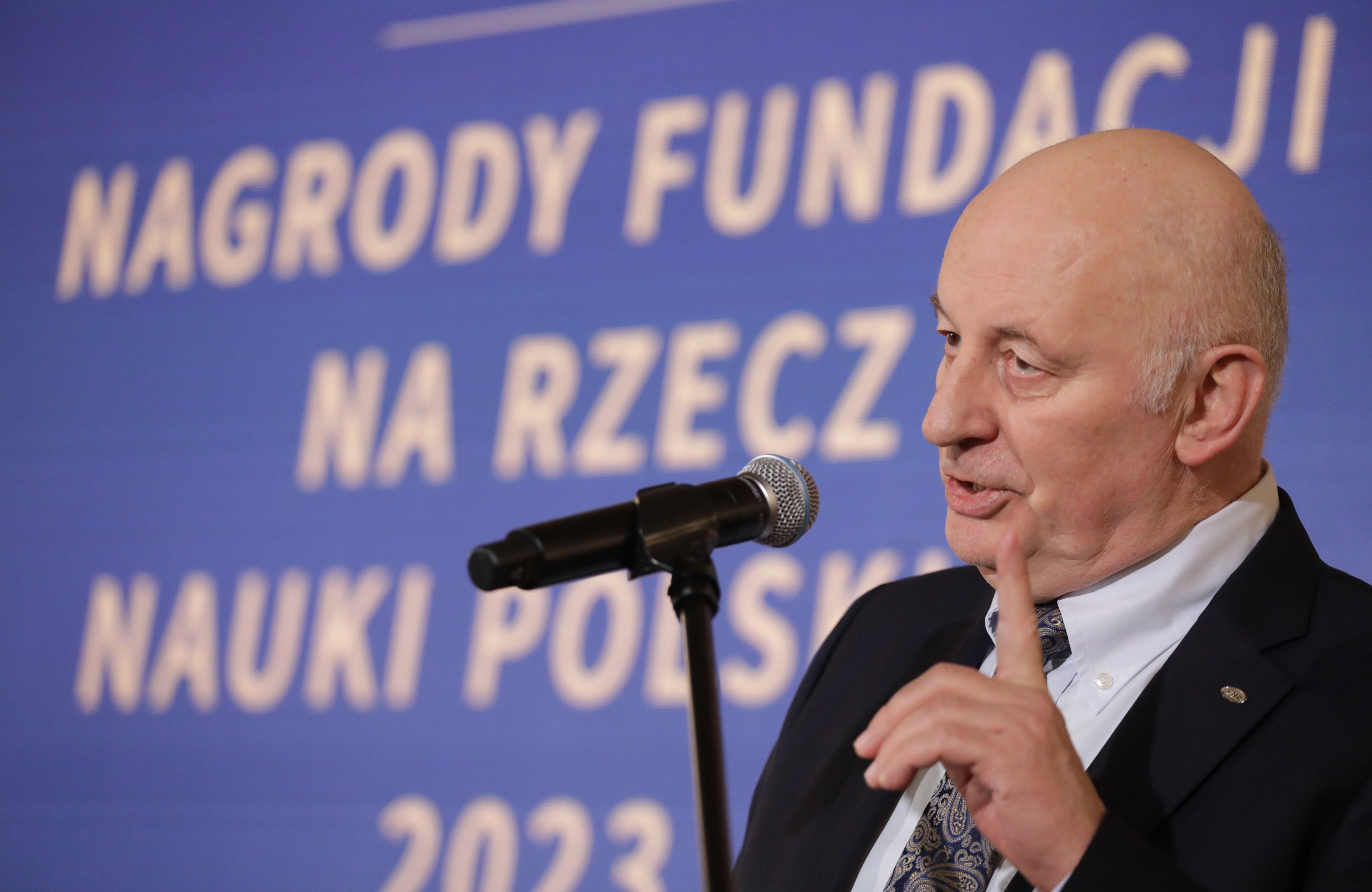 Łysawy mężczyzna przemawia na tle napisu Nagrody Fundacji na rzecz Nauki Polskiej