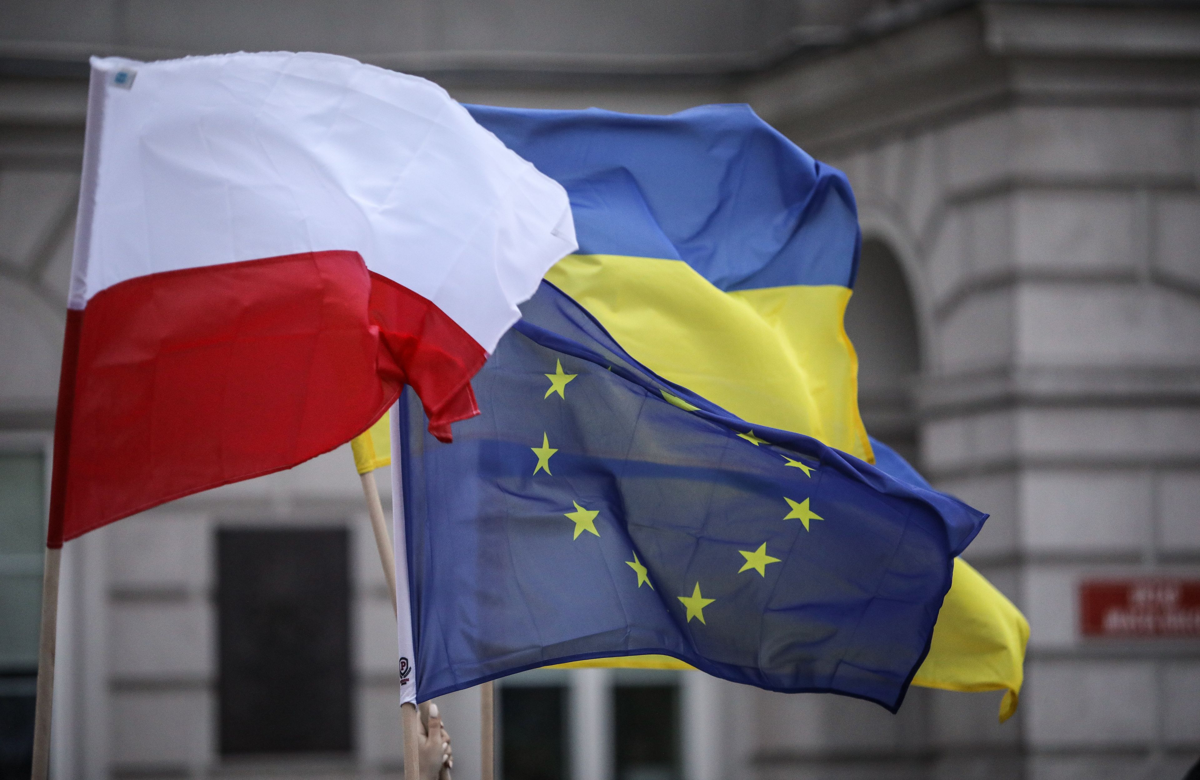 Na zdjęciu są trzy flagi: biało czerwona, niebiesko-żółta oraz niebieska z 12 żółtymi gwiazdkami
