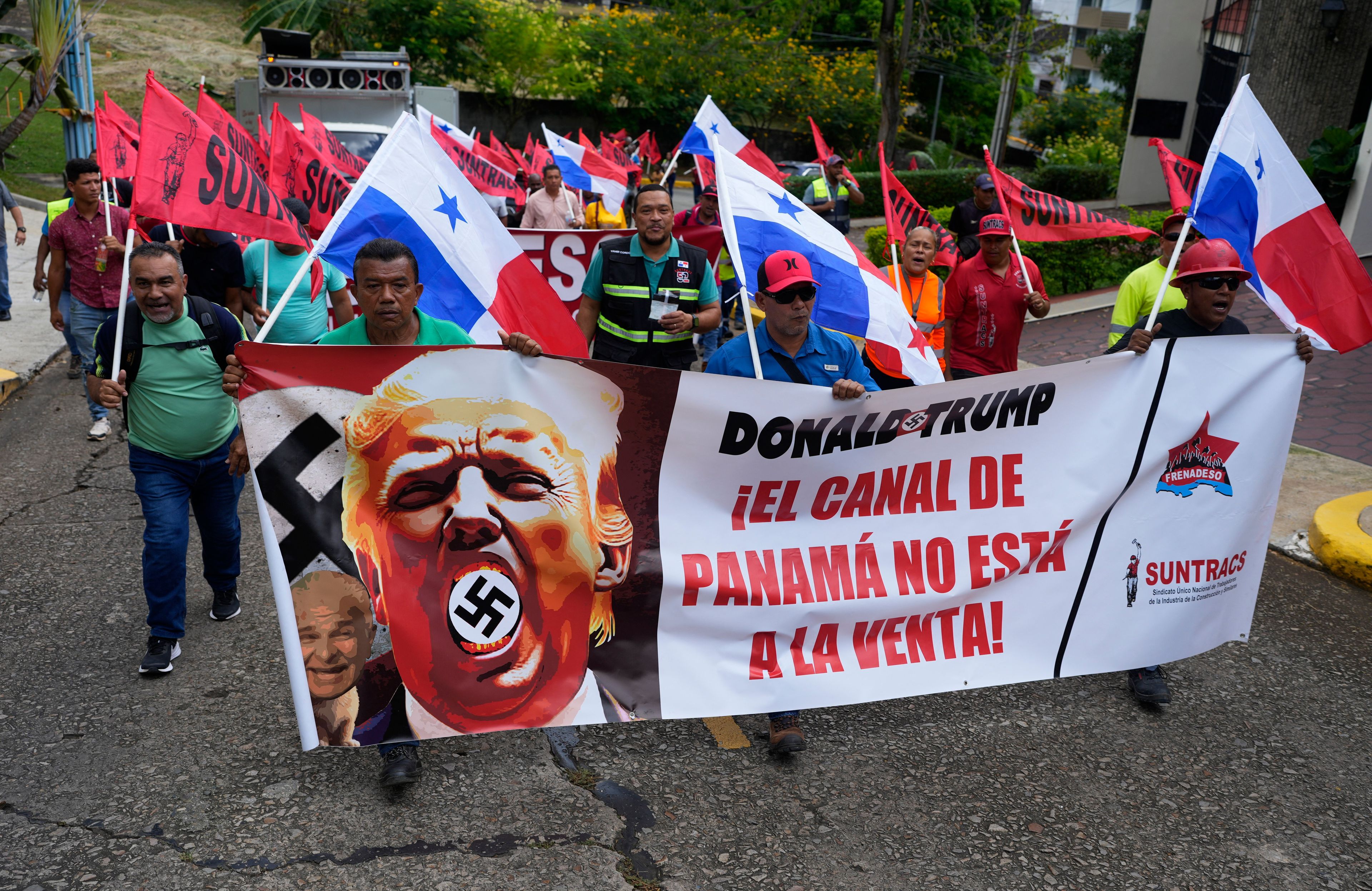 Demonstranci niosą transparent z napisem „Kanał Panamski nie jest na sprzedaż” z wizerunkiem Donalda Trumpa ze swastyką przed siedzibą ambasady USA w Panama City, 20.01.2025 r