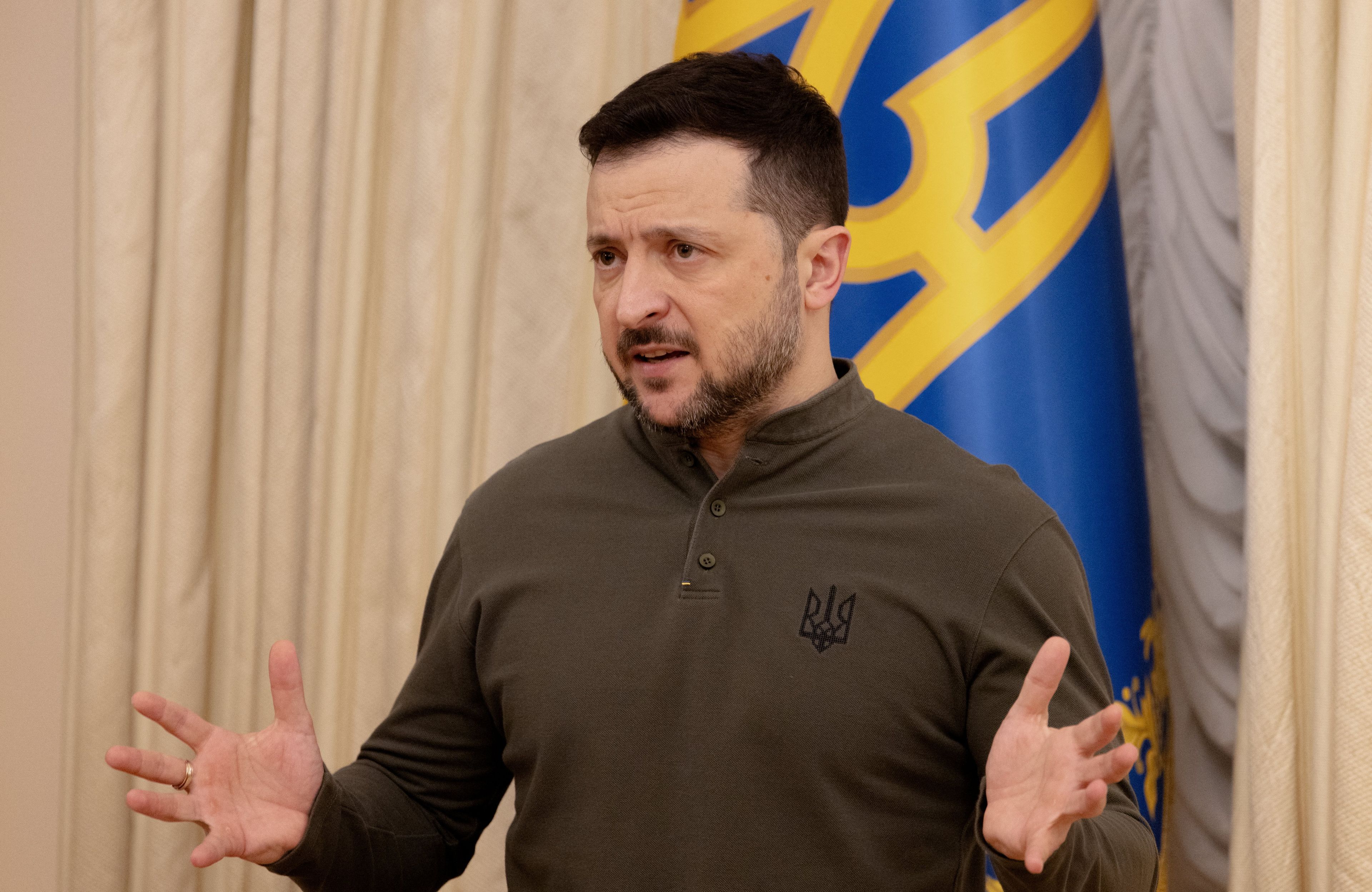 Mężczyzna w bluzie khaki mówi gestykulując