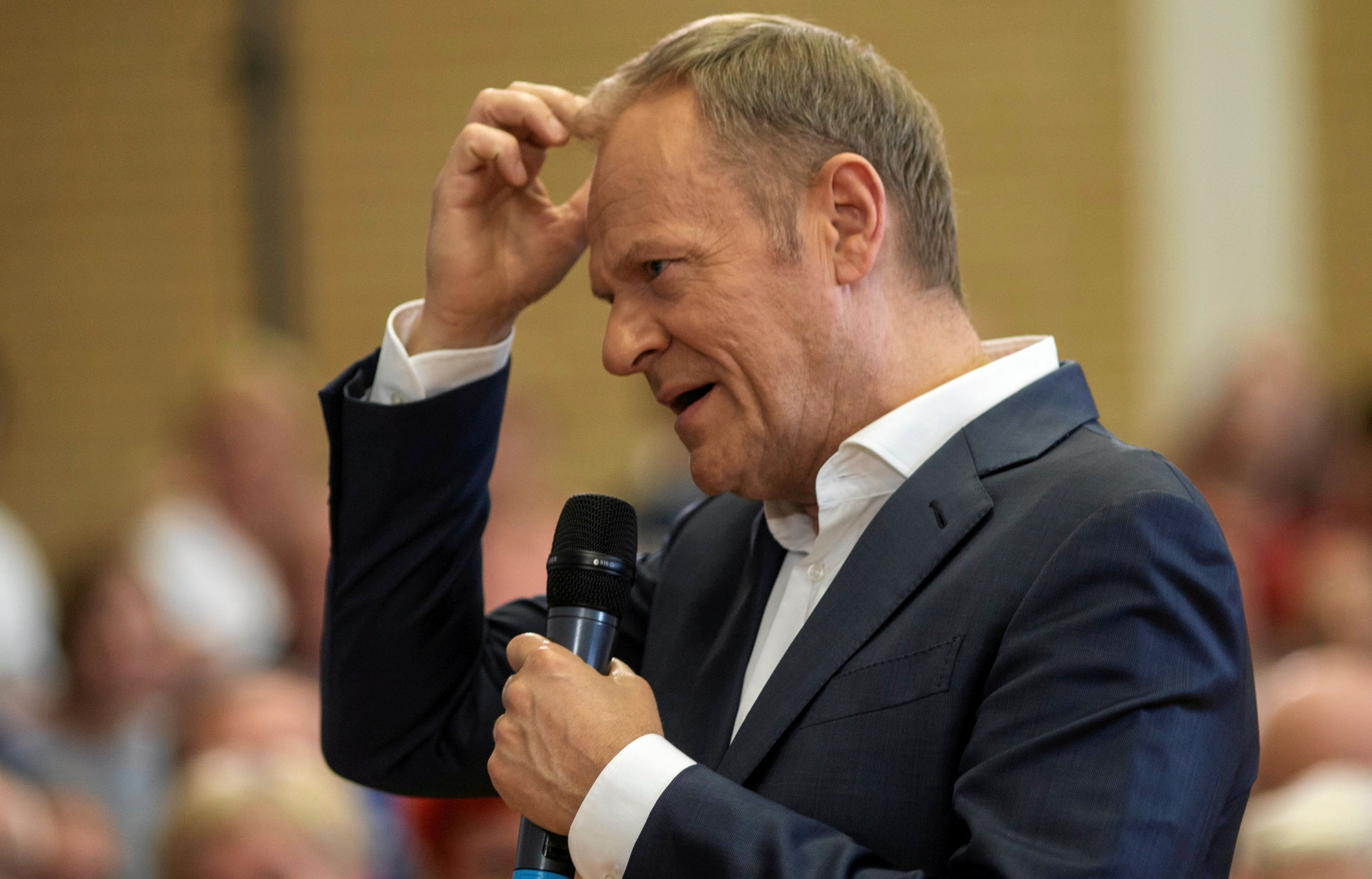 Tusk na spotkaniu przedwyborczym dotyka głowy w geście zastanawiania się