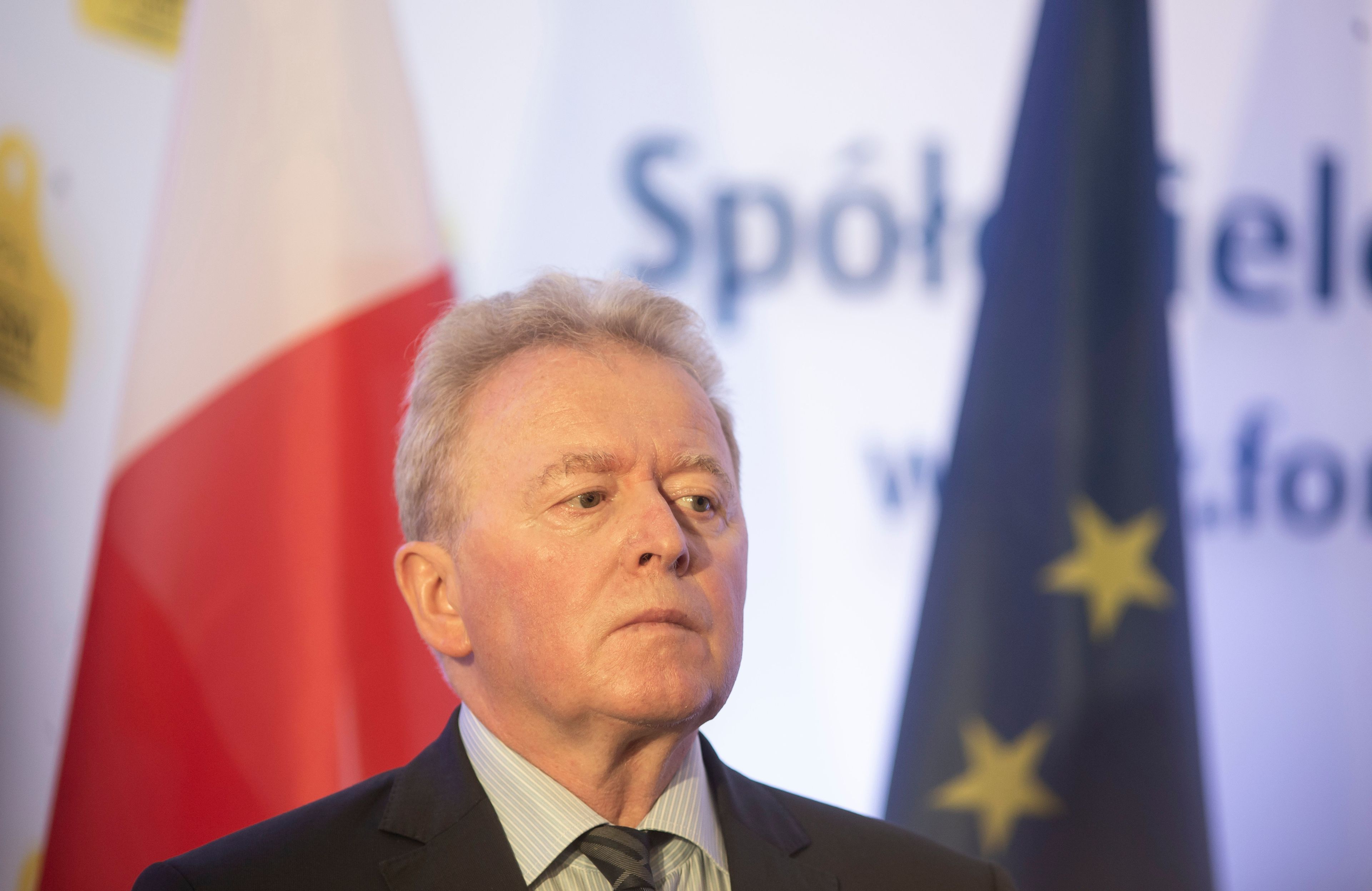 Komisarz rolnictwa Janusz Wojciechowski na tle flag polski u Unii Europejskiej