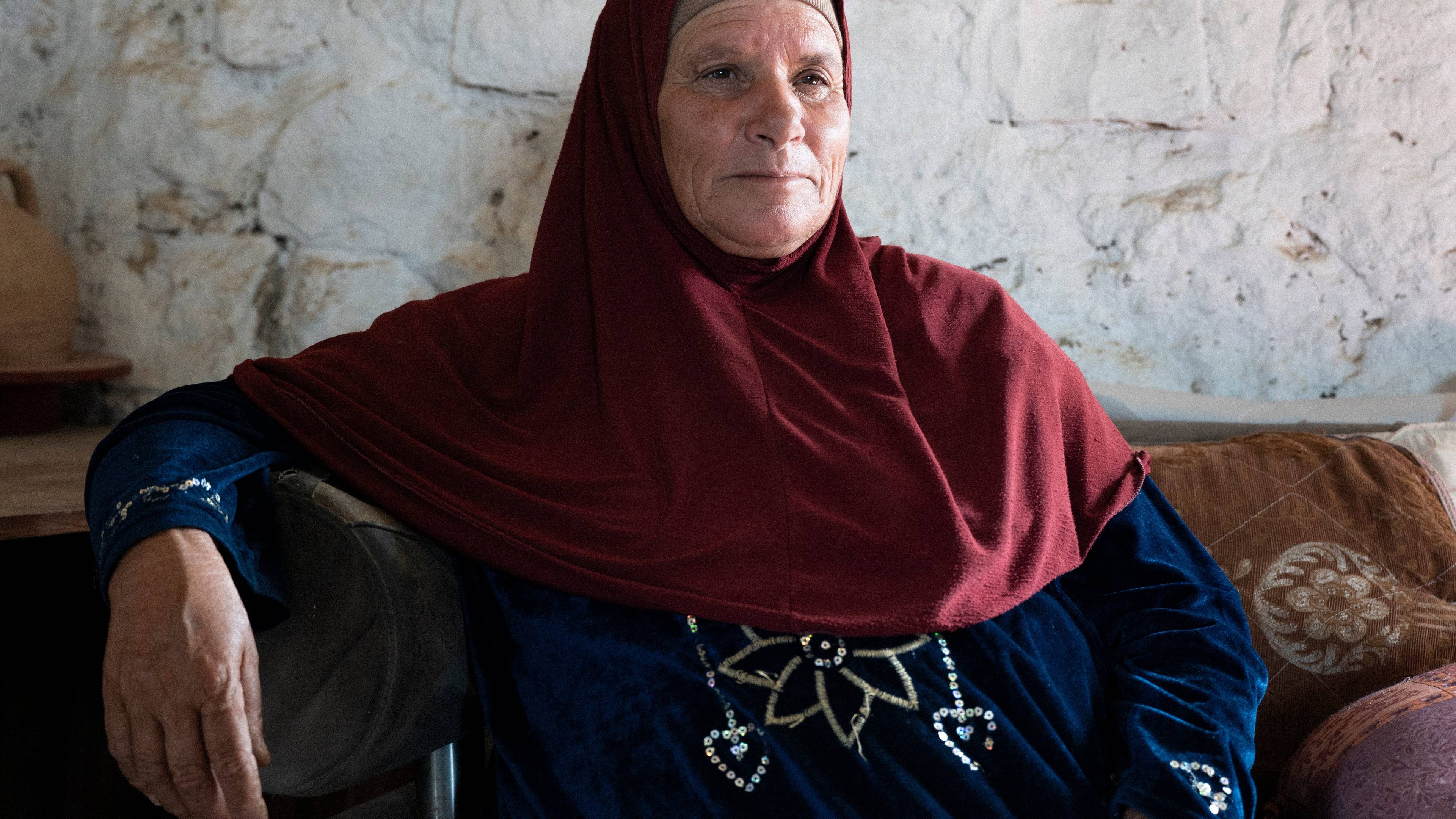 Starsza kobieta w chadorze siedzi na na kanapie