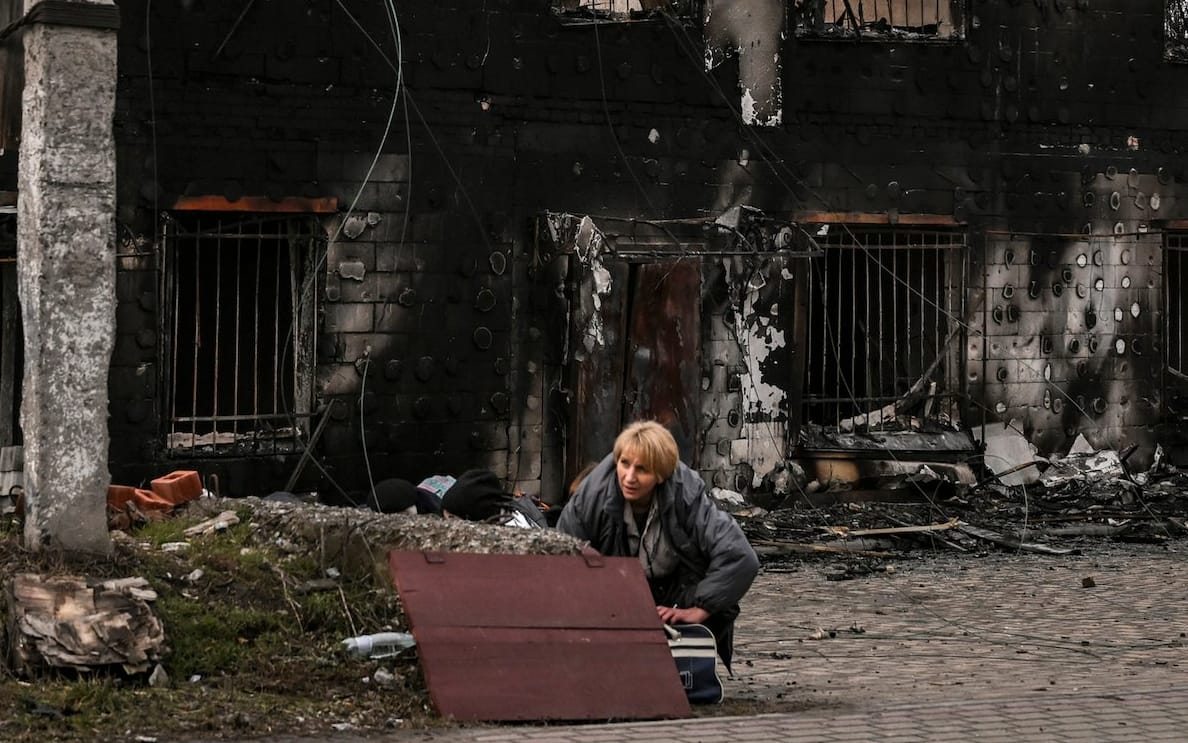 A woman takes cover from shelling in the city of Bucha, west of Kyiv, on March 4, 2022. - The UN Human Rights Council on March 4, 2022, overwhelmingly voted to create a top-level investigation into violations committed following Russia's invasion of Ukraine. More than 1.2 million people have fled Ukraine into neighbouring countries since Russia launched its full-scale invasion on February 24, United Nations figures showed on March 4, 2022. (Photo by ARIS MESSINIS / AFP)