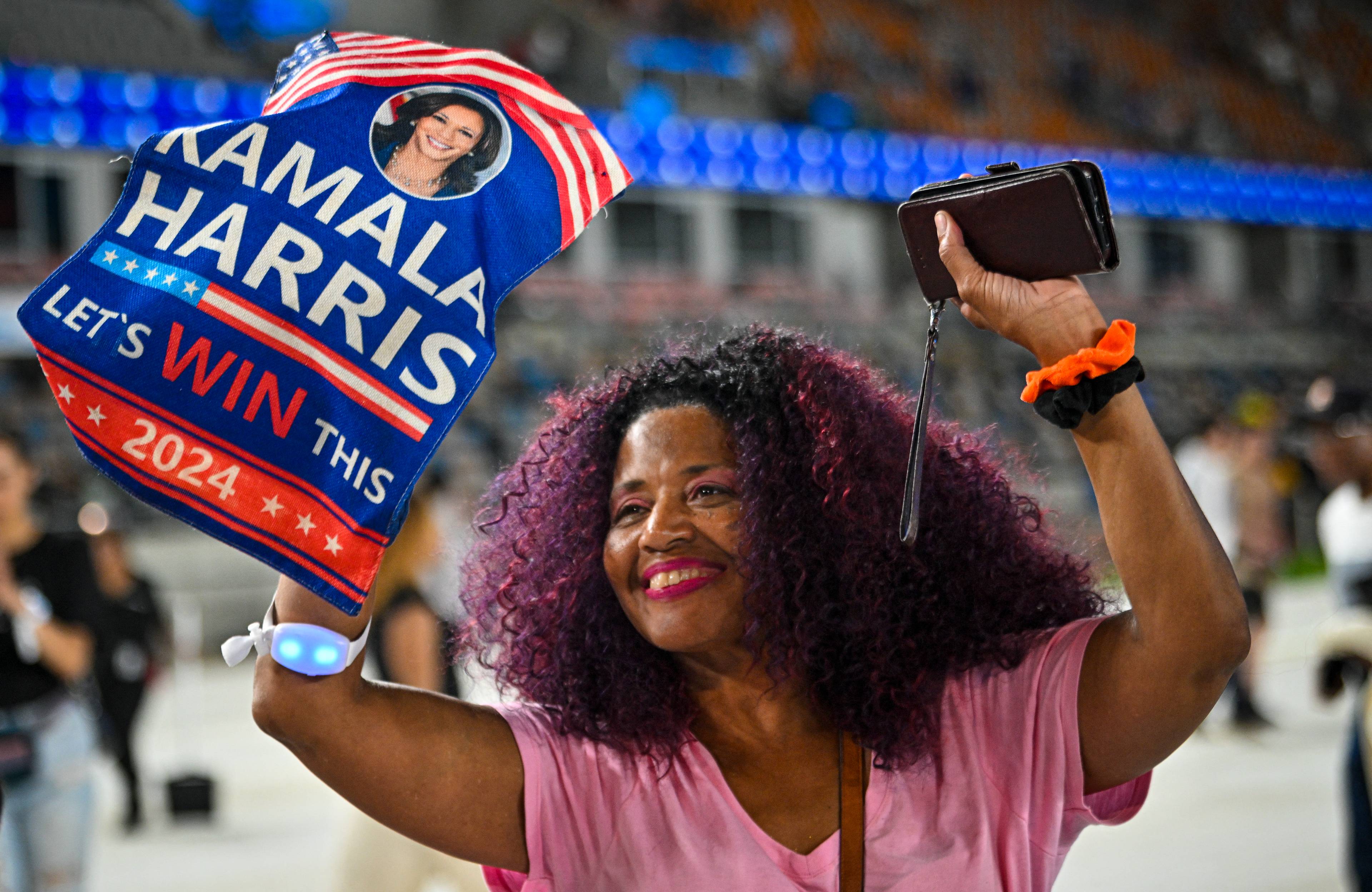 Czarnoskóra kobieta z afro trzymająca plakat „Kamala Harris, win this!"