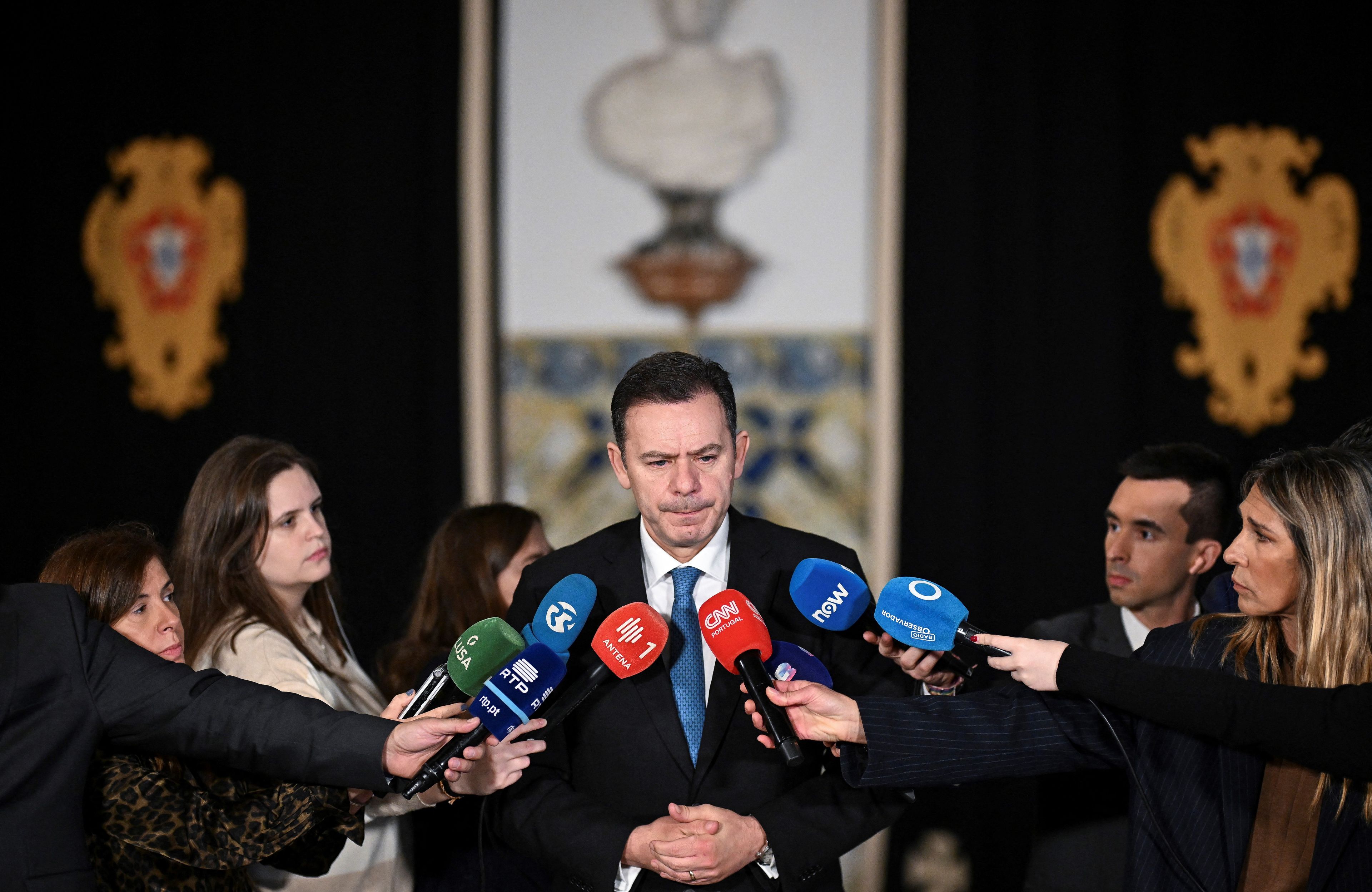Premier Portugalii Luis Montenegro podczas konferencji prasowej. Dziennikarze trzymają mikrofony przy jego twarzy