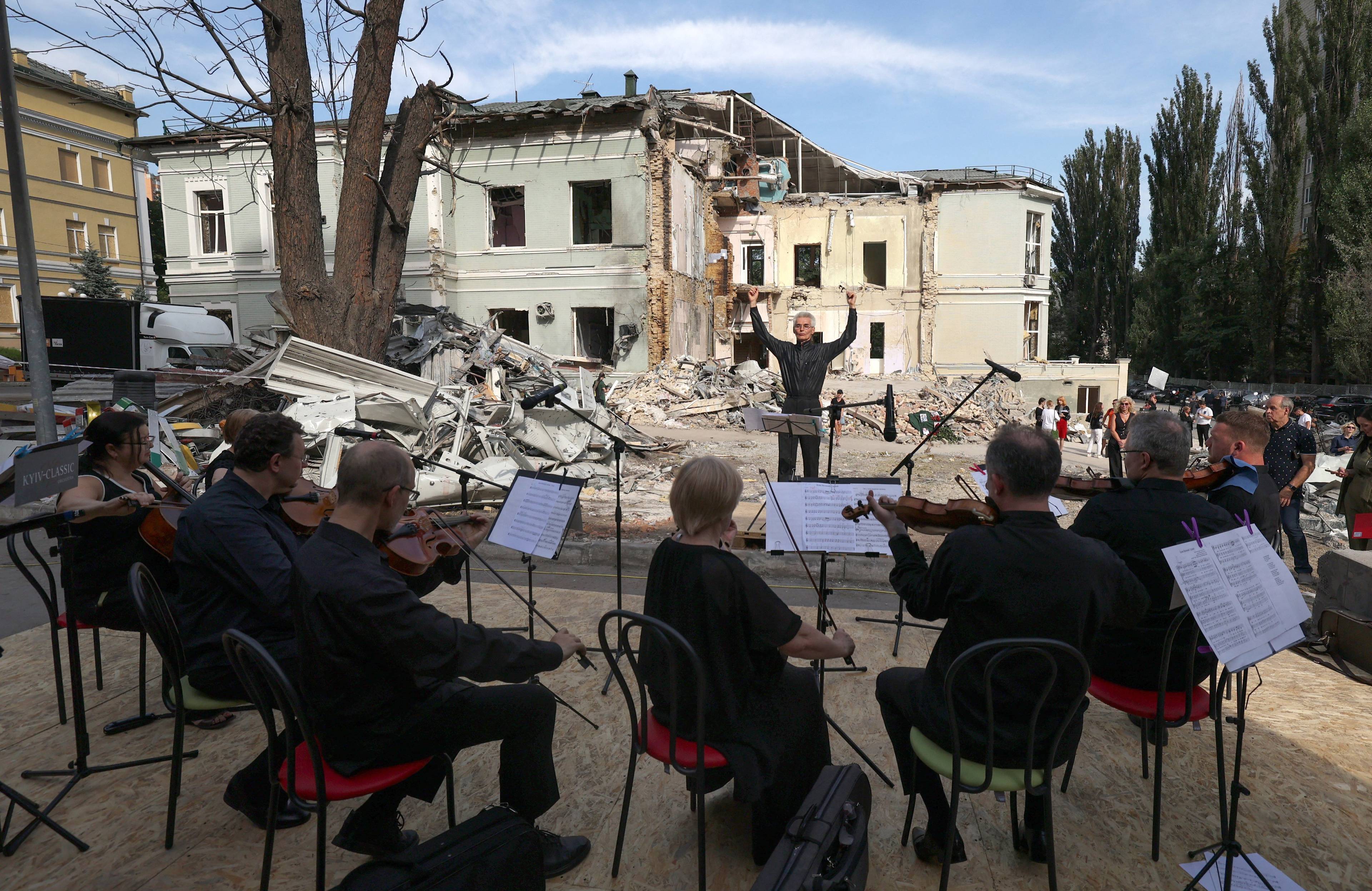 Orkiestra kameralna gra przed gruzami budynku