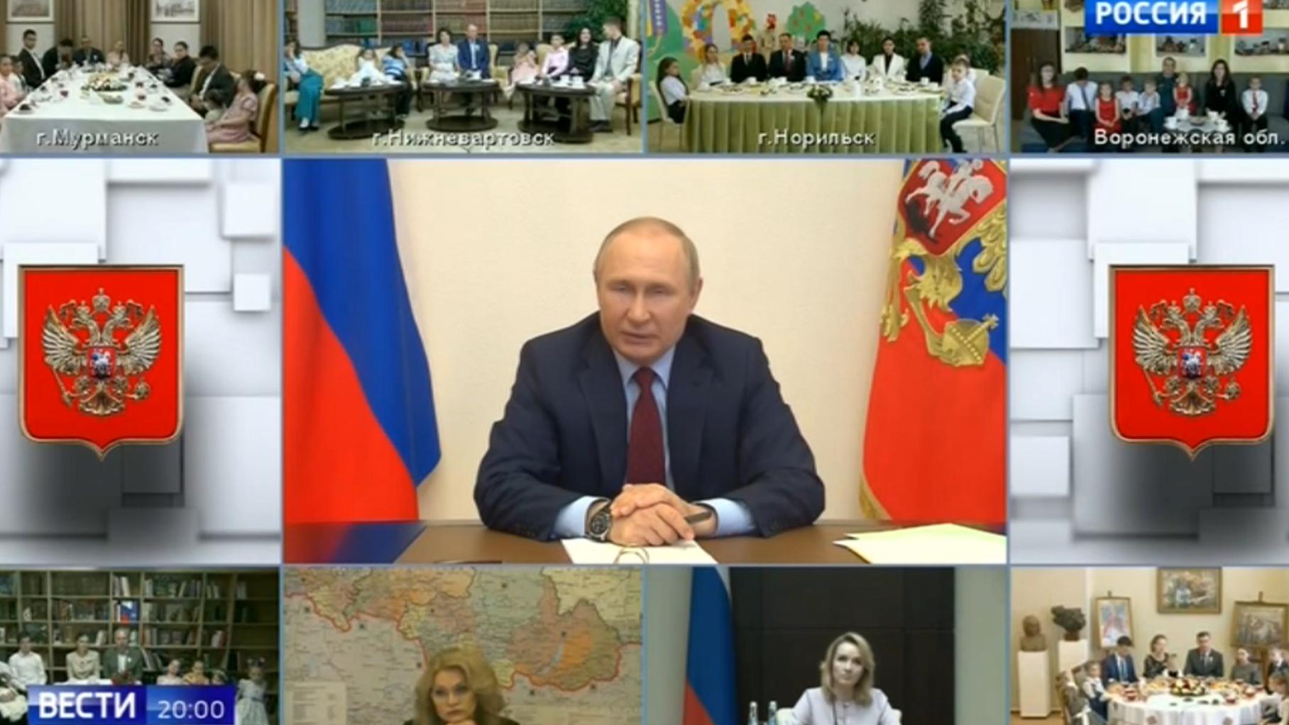 Telekonferencja Putina z wielodzietnymi rodzinami. Siedzą one na krzesłach przed monitorami