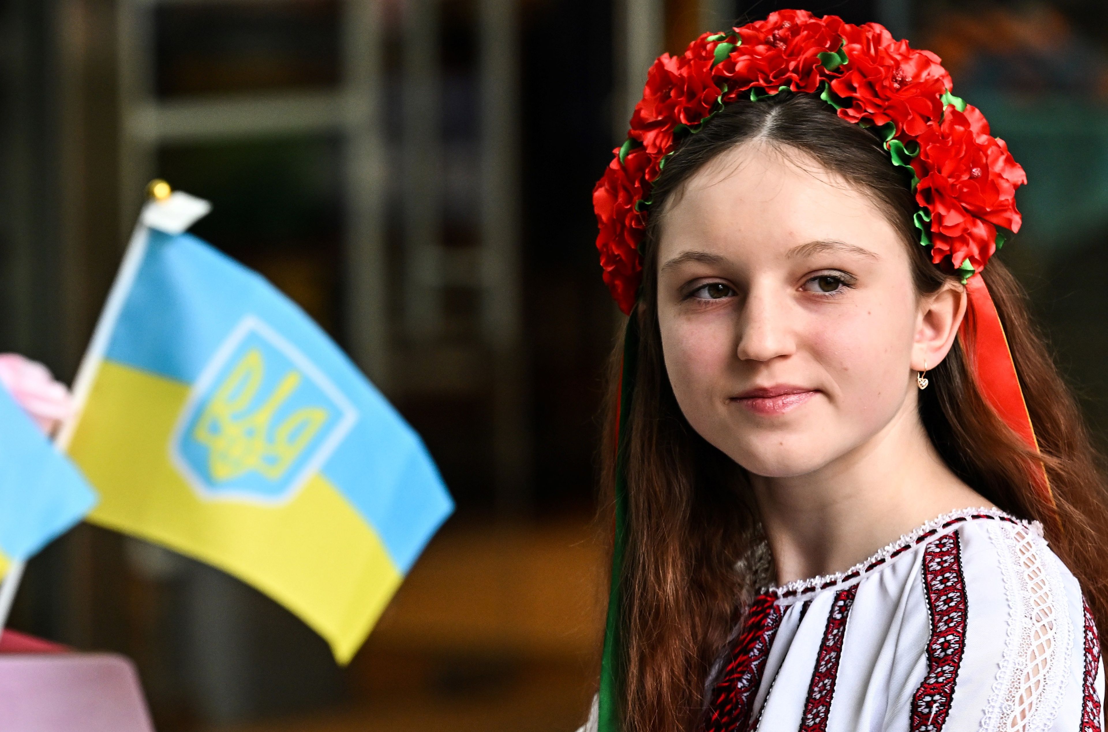 Nastolatka w ukraińskim stroju ludowym obok flag Ukrainy