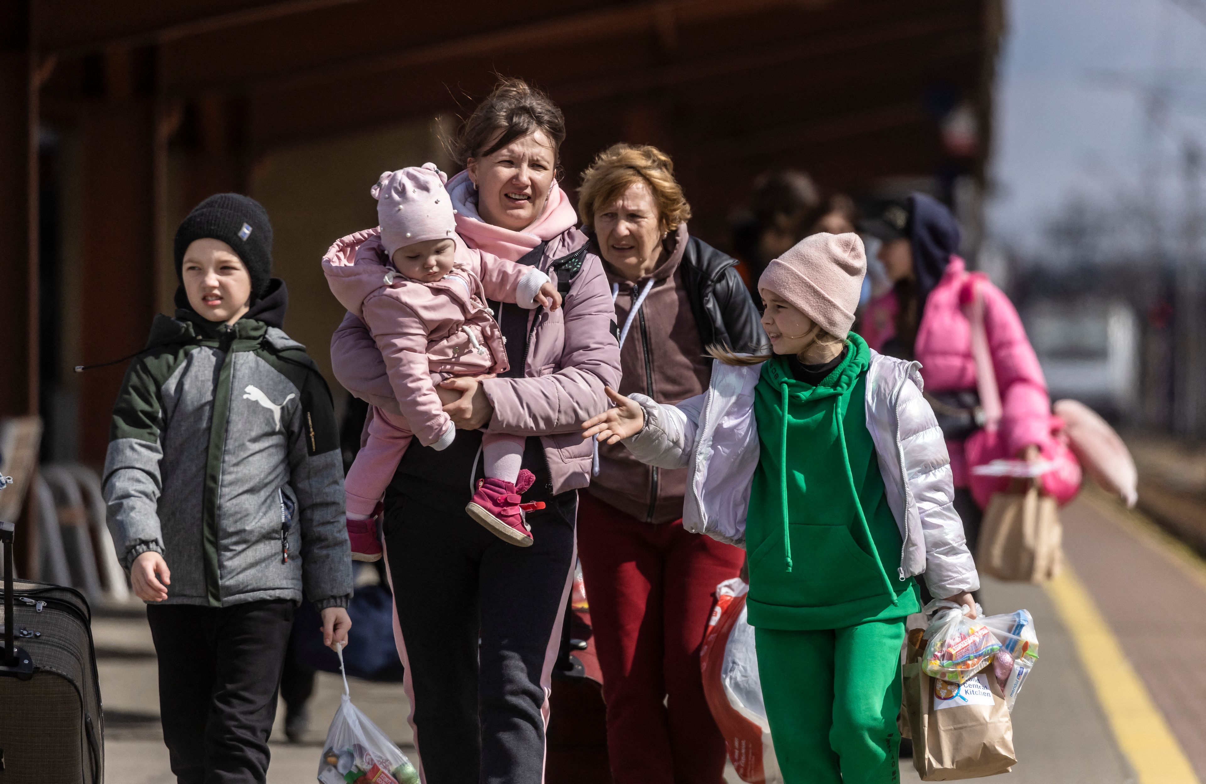 Na zdjęciu dwie kobiety i trójka dzieci. Młodsza kobieta trzyma na rękach małe dziecko.