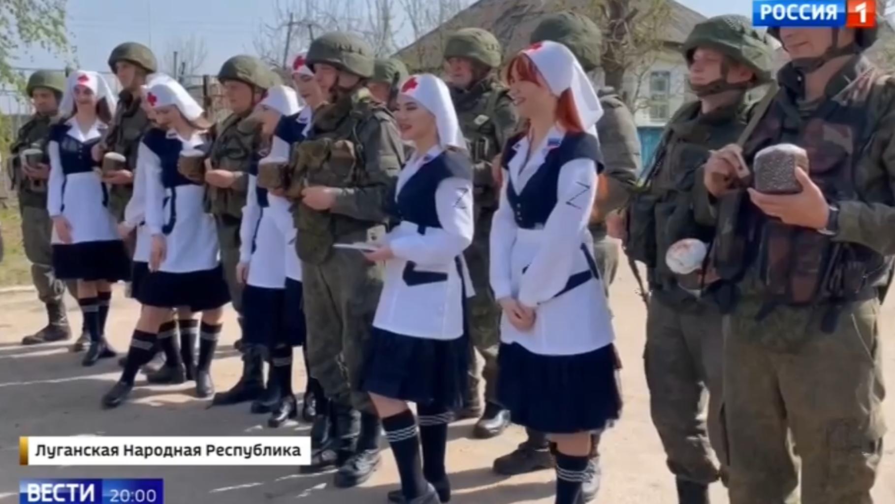 Przebrane za seksowne sanitaruuszki z literą Z młode kobiety pozuja do zdjęcia z żołnierzami, którym przyniosły święcona ciasta
