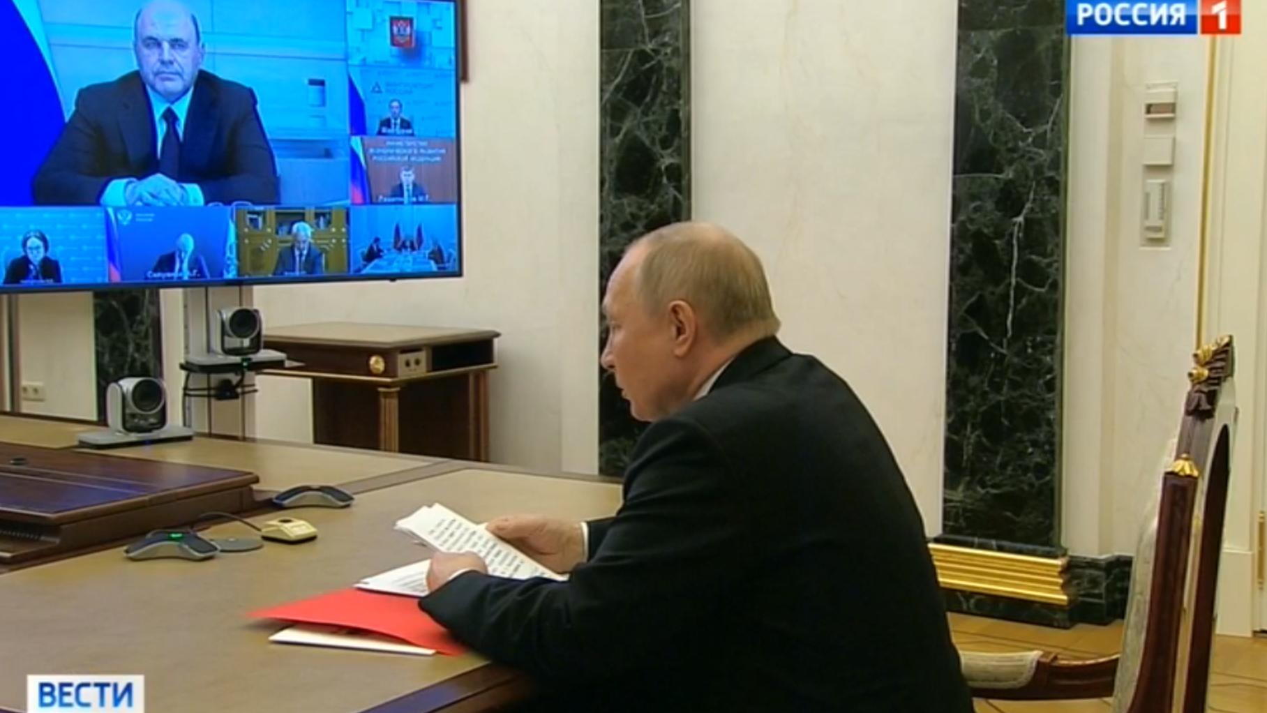 Męzczyzna (Putin) w czasie telekonferencji czyta z kartki
