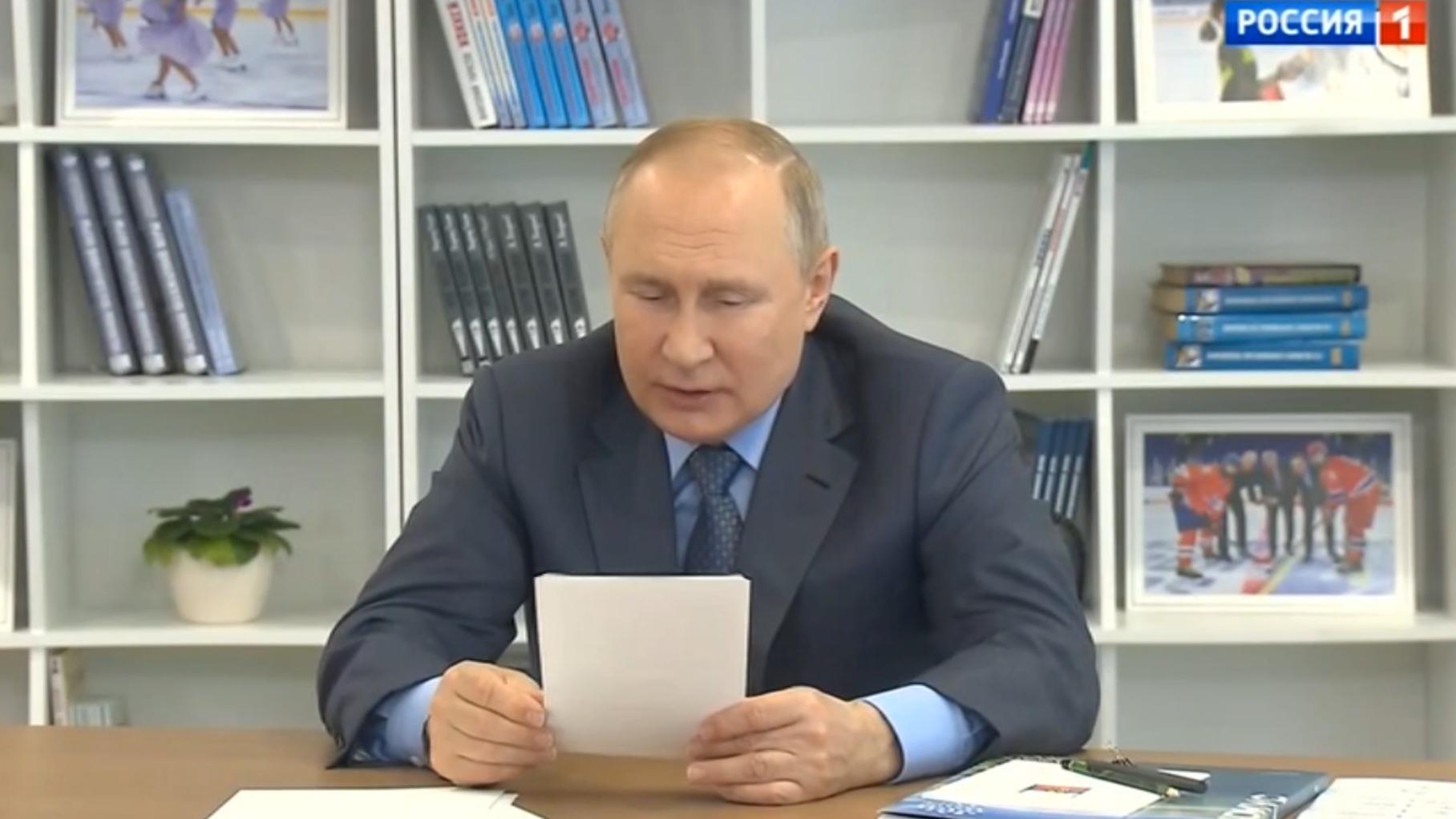 Putin czyta z kartki. W tle półki z dziecięcymi książkami
