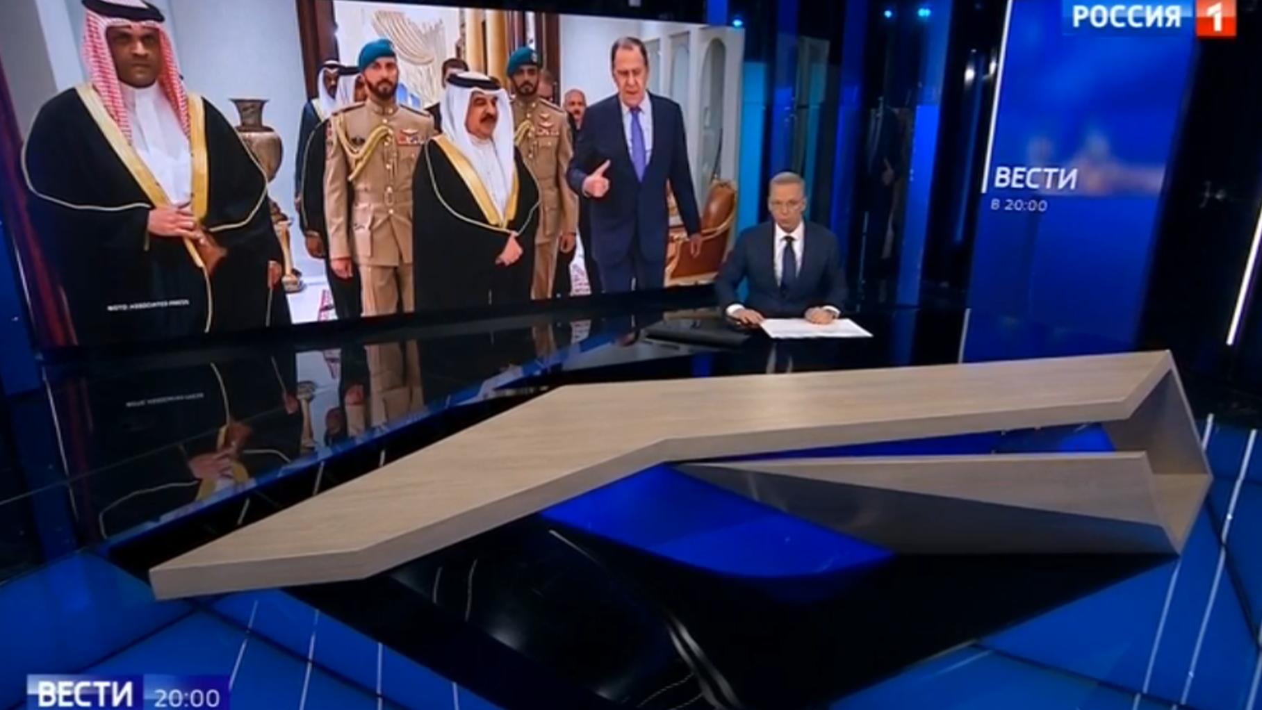 Studio telewizyjne, prezenter. w tle: zdjęcie ze spotkania dyplomatycznego dostojników w szatach arabskich i w stroju europejskim