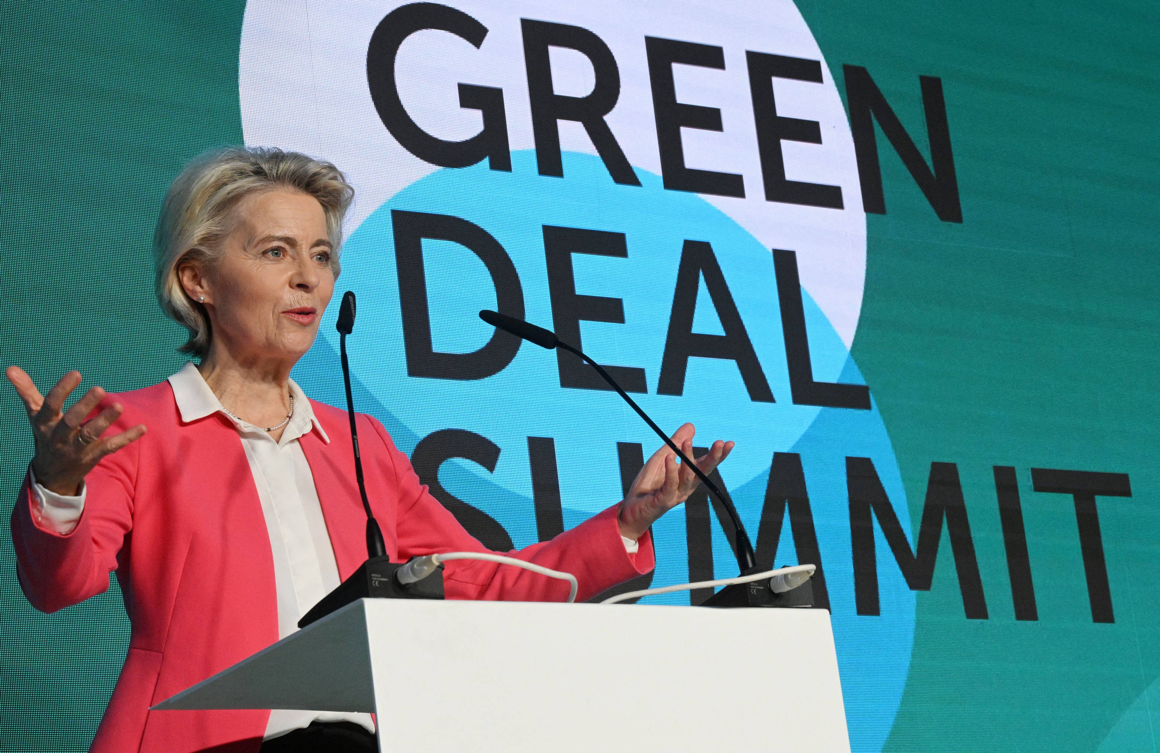 Ursula von der Leyen w czerwonej marynarce na zielonym tle, za nią napis green deal summit