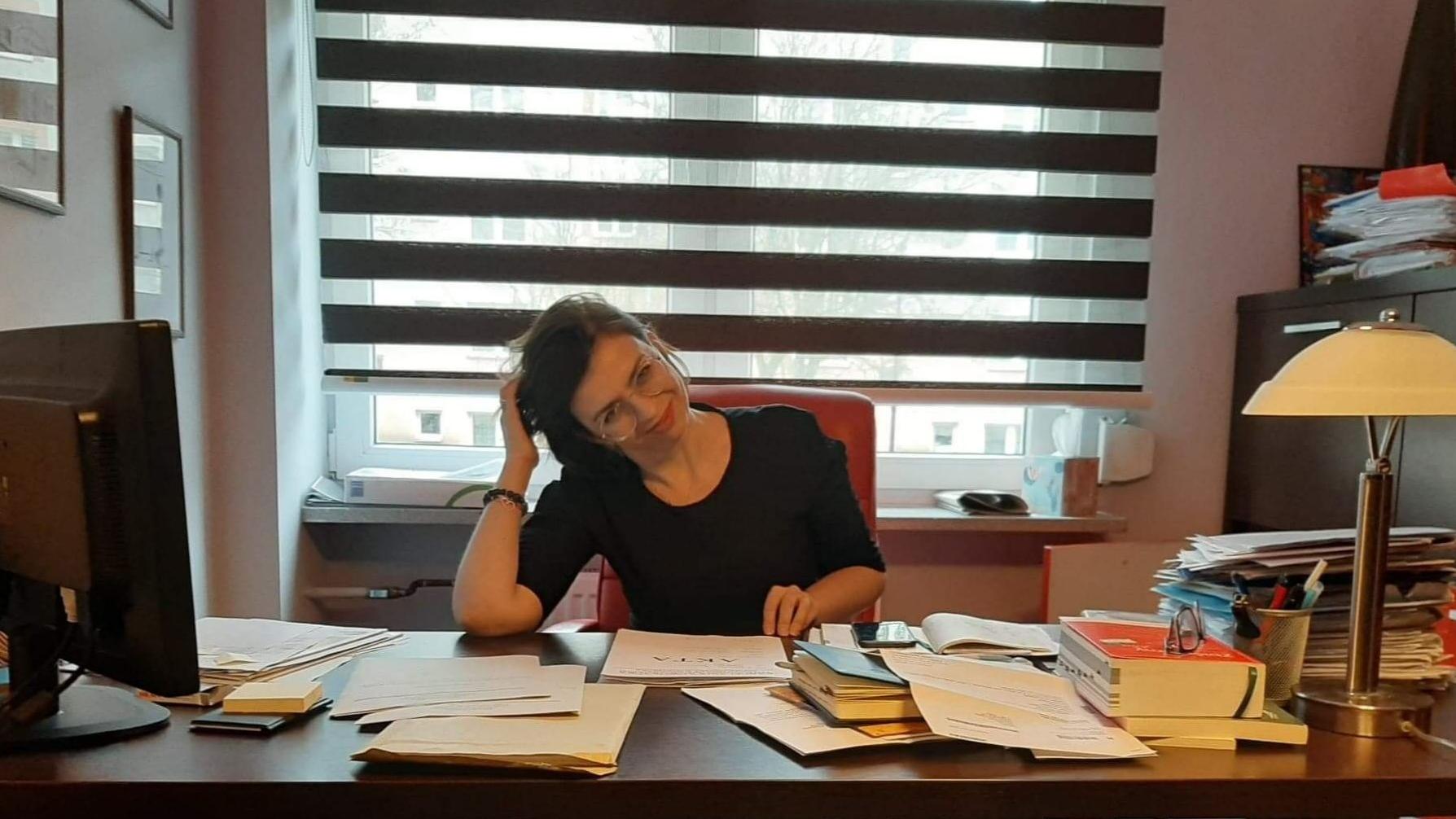 Monika Sokołowska w swoim biurze, za biórkiem zawalonym aktami