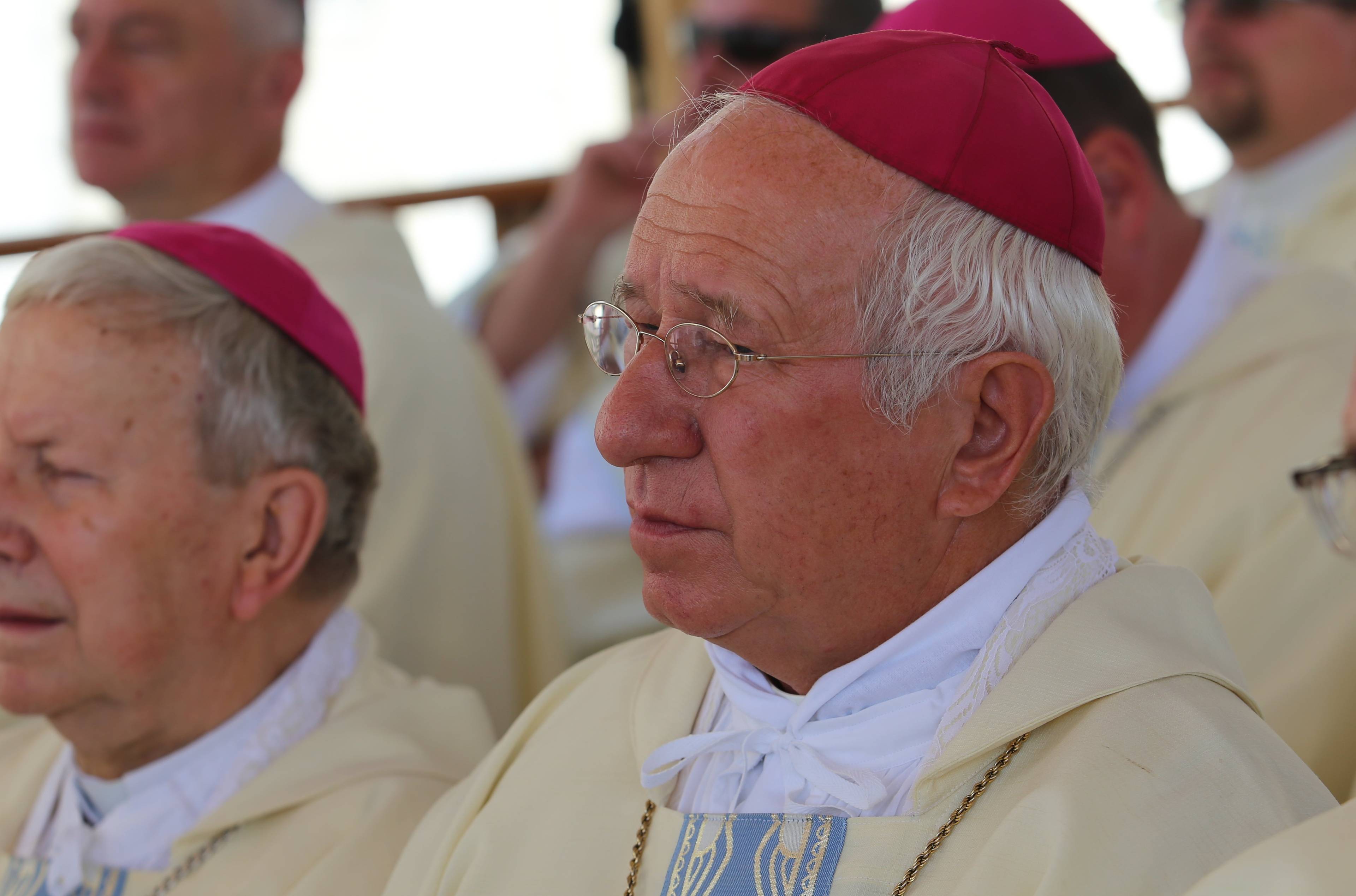 Biskup Andrzej Dziuba siedzi zasmucony na kościelnej uroczystości.
